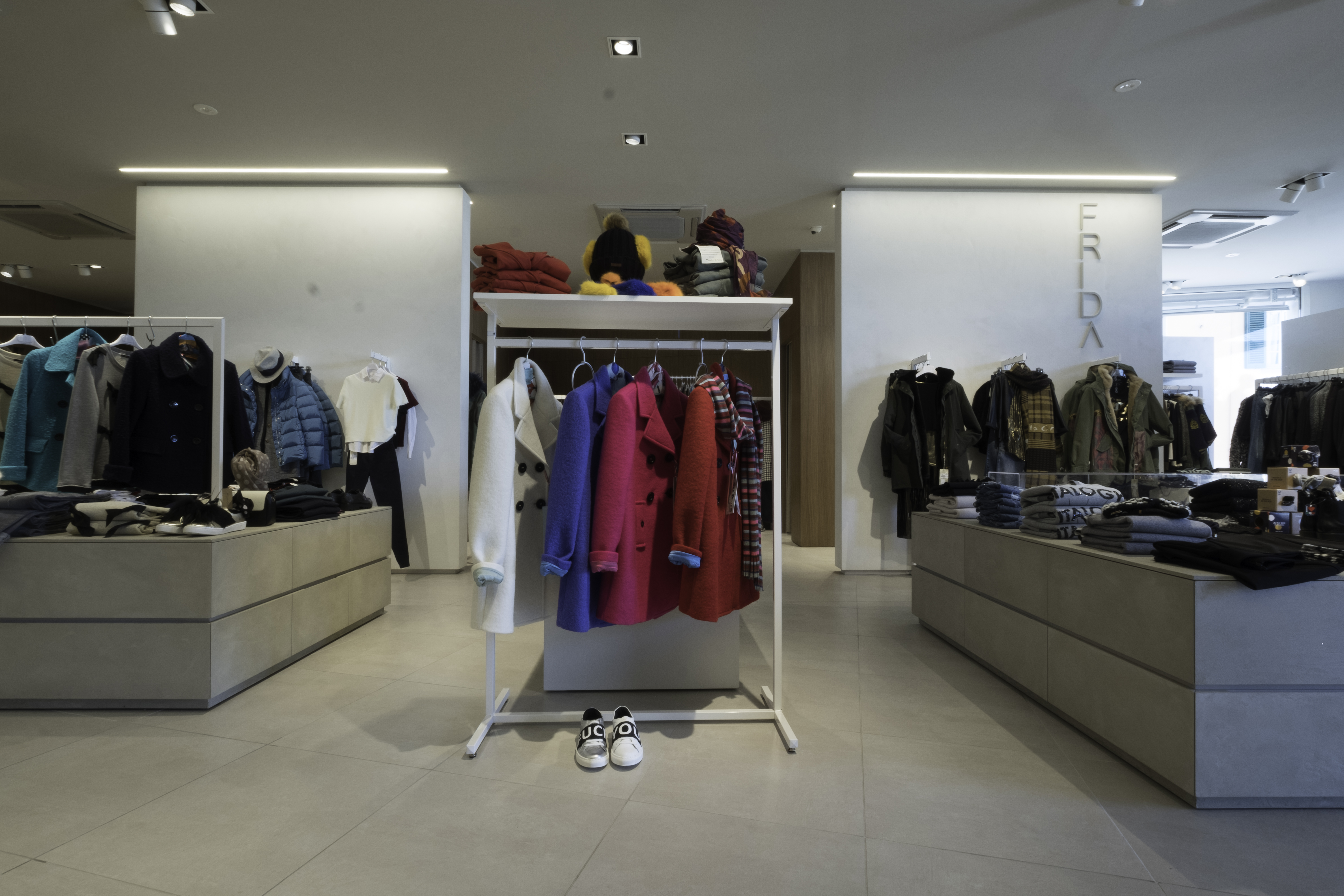 Bright, large-format tiles in a clothing store with clothing racks.