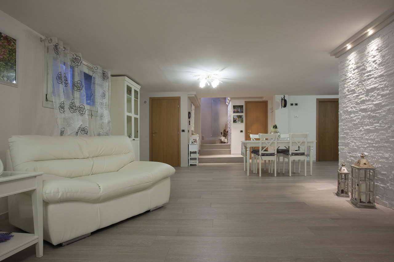 Living room with light grey wood-effect tiles and a white stone-effect wall.