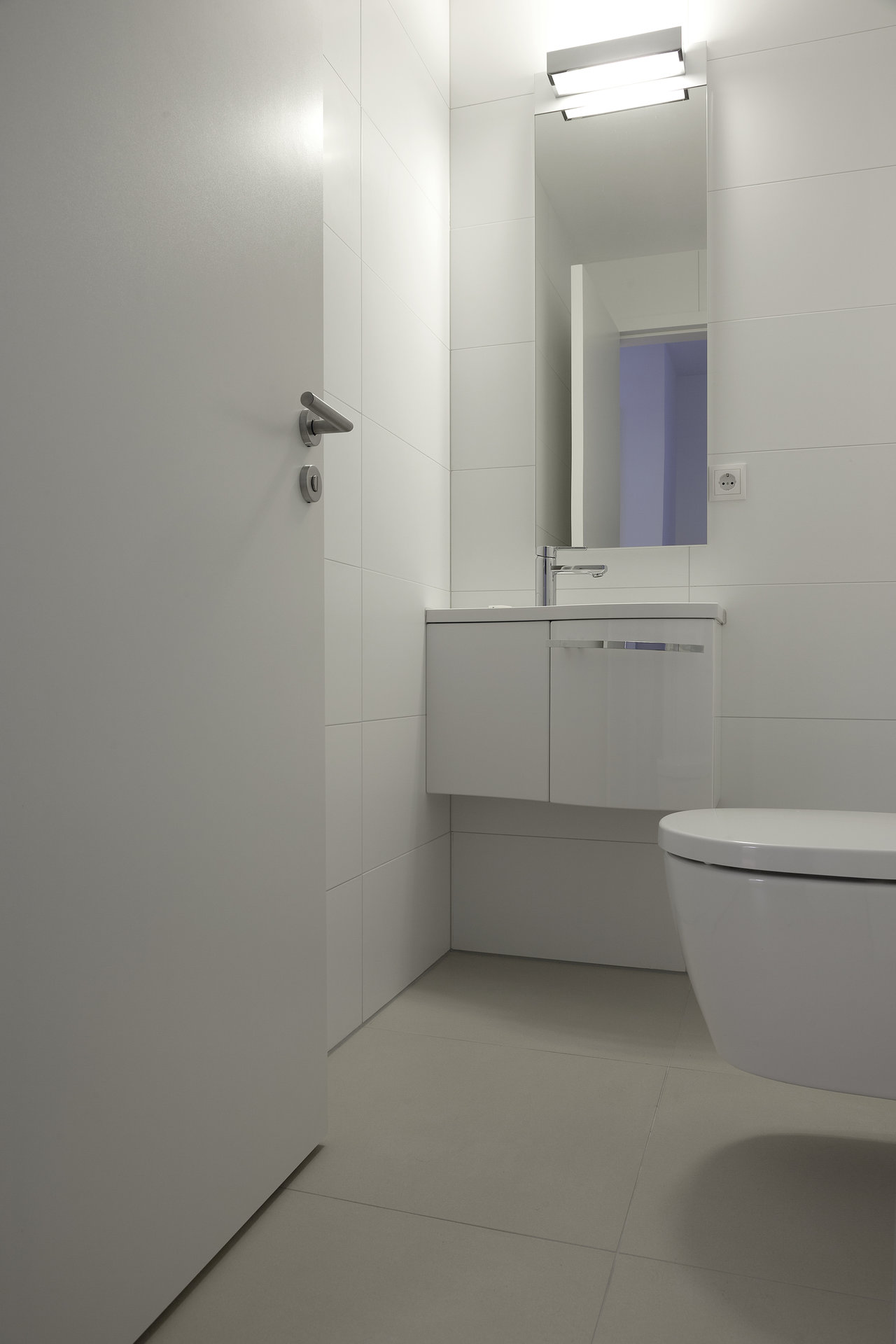 Minimalist WC with elegant white wall and floor tiles.