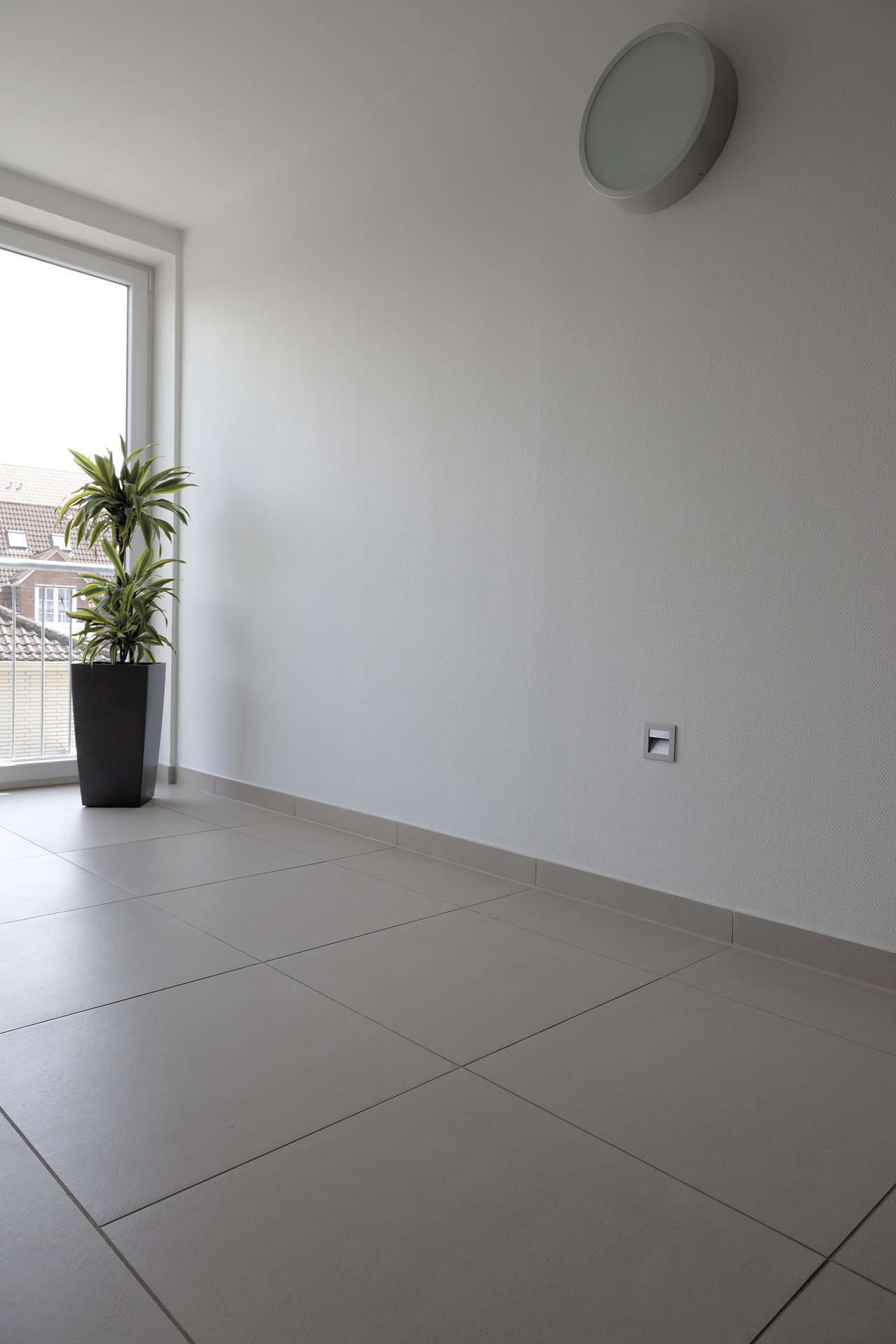 Modern interior with light grey floor tiles, large window, and a houseplant.