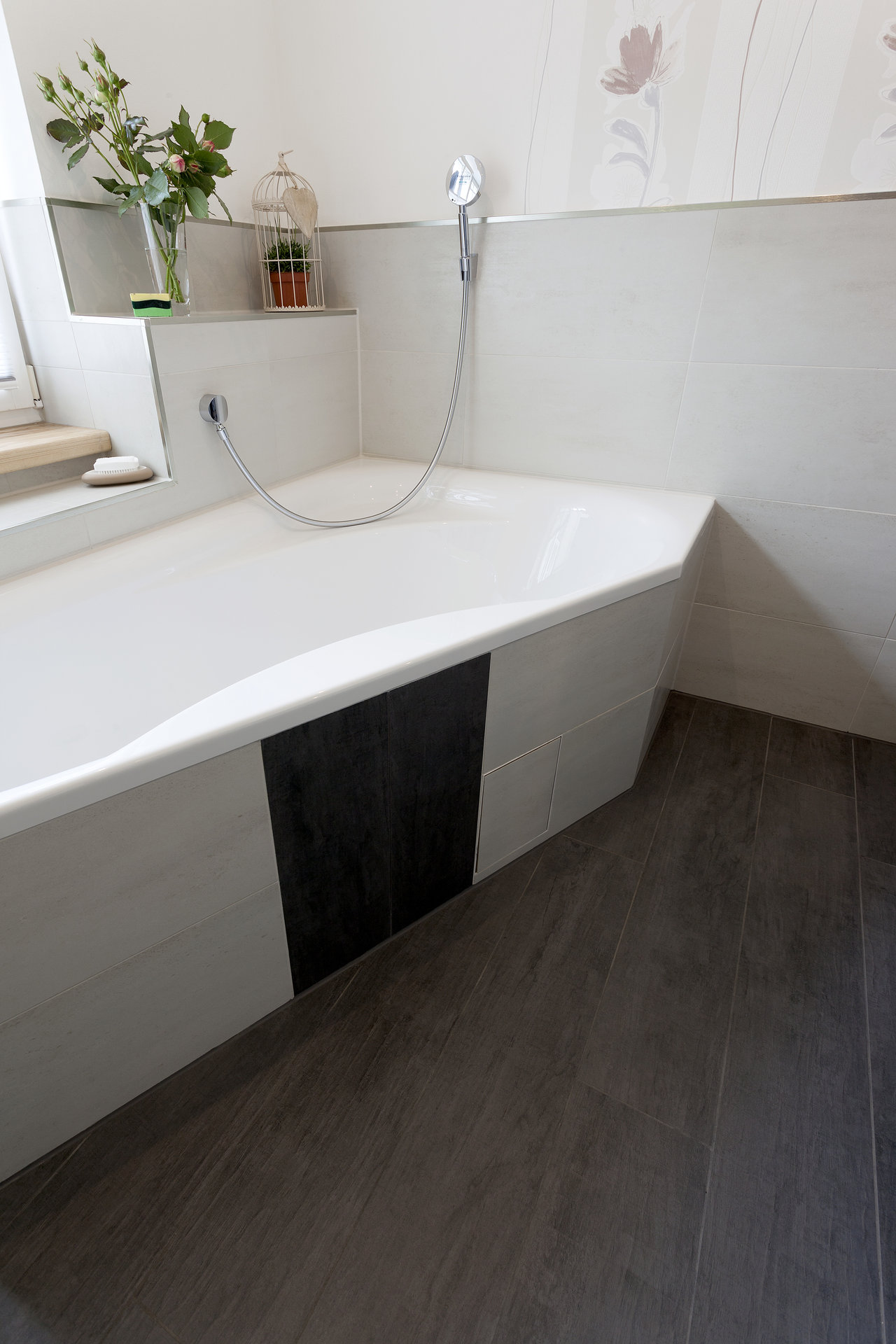 Dunkle Bodenfliesen und weiße Wandfliesen mit schwarzem Akzent an der Badewanne.