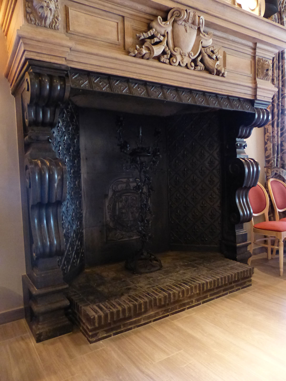 Light wood-look tile floor in front of an opulent wooden fireplace.