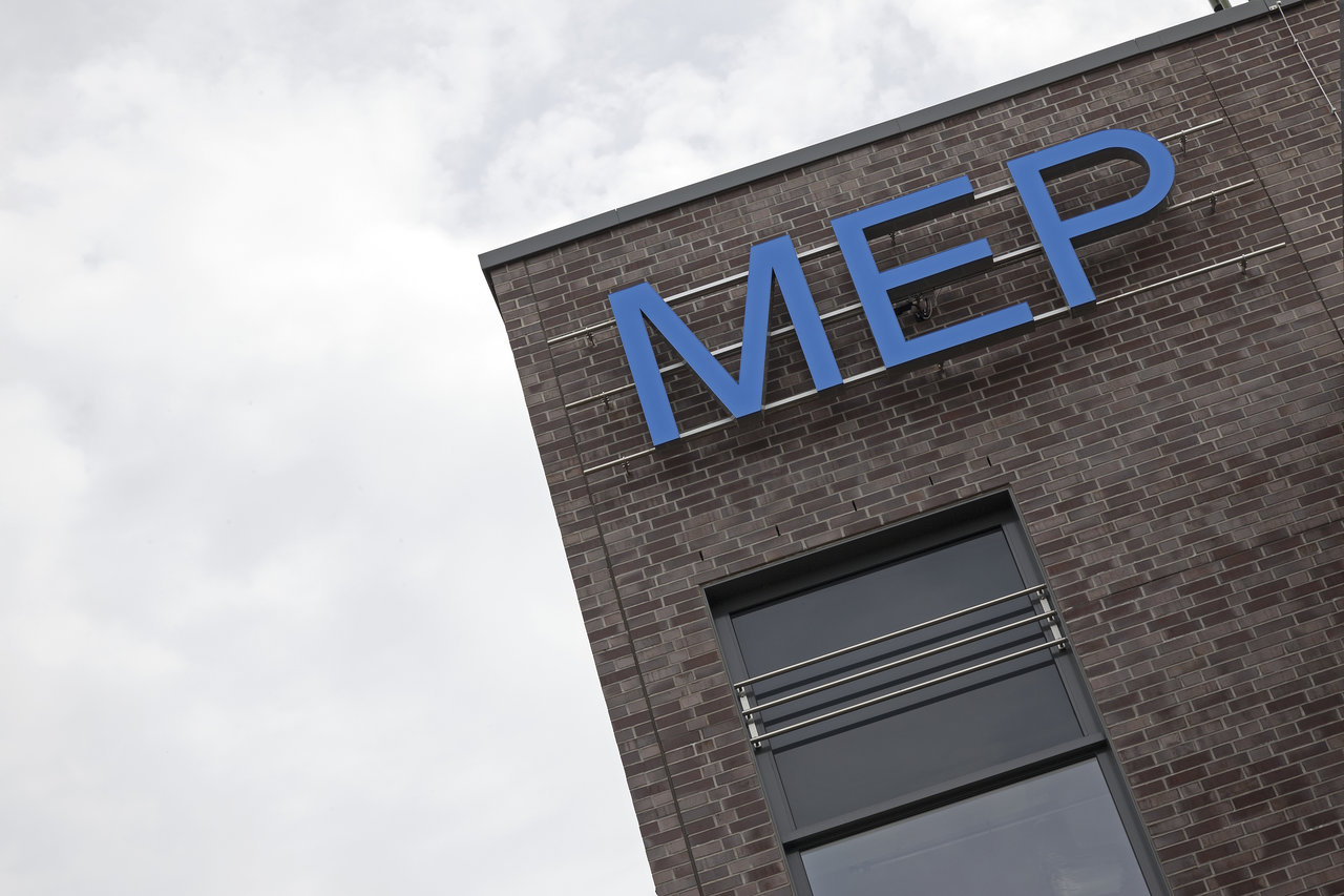 MEP lettering on the facade of a dark brick building.