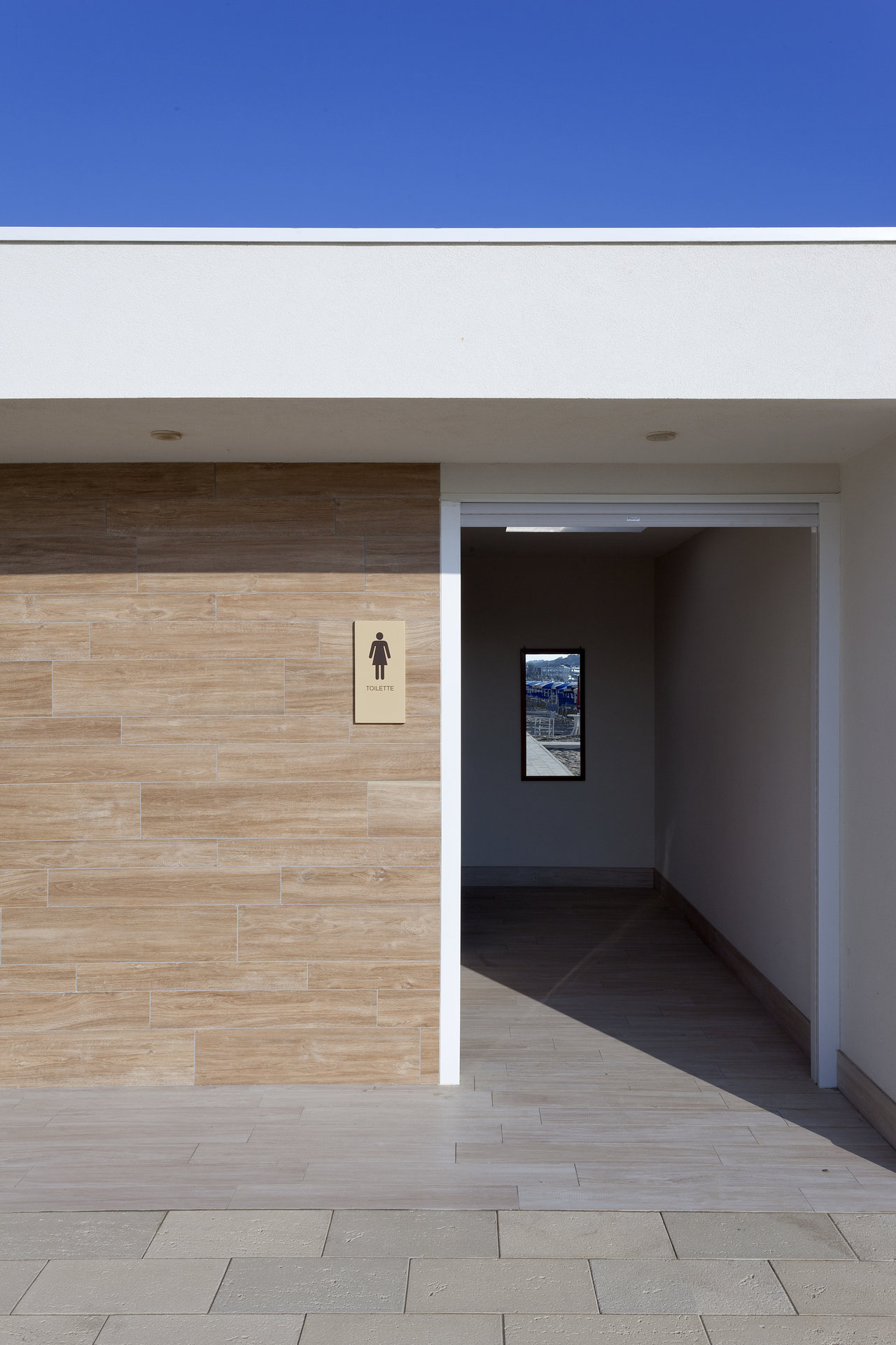 Modern entrance area with wood-effect wall tiles and light floor tiles.