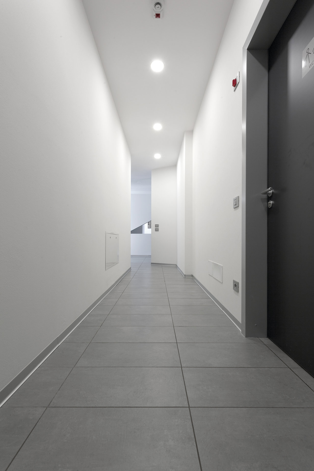 Modern hallway with light grey, large-format floor tiles.