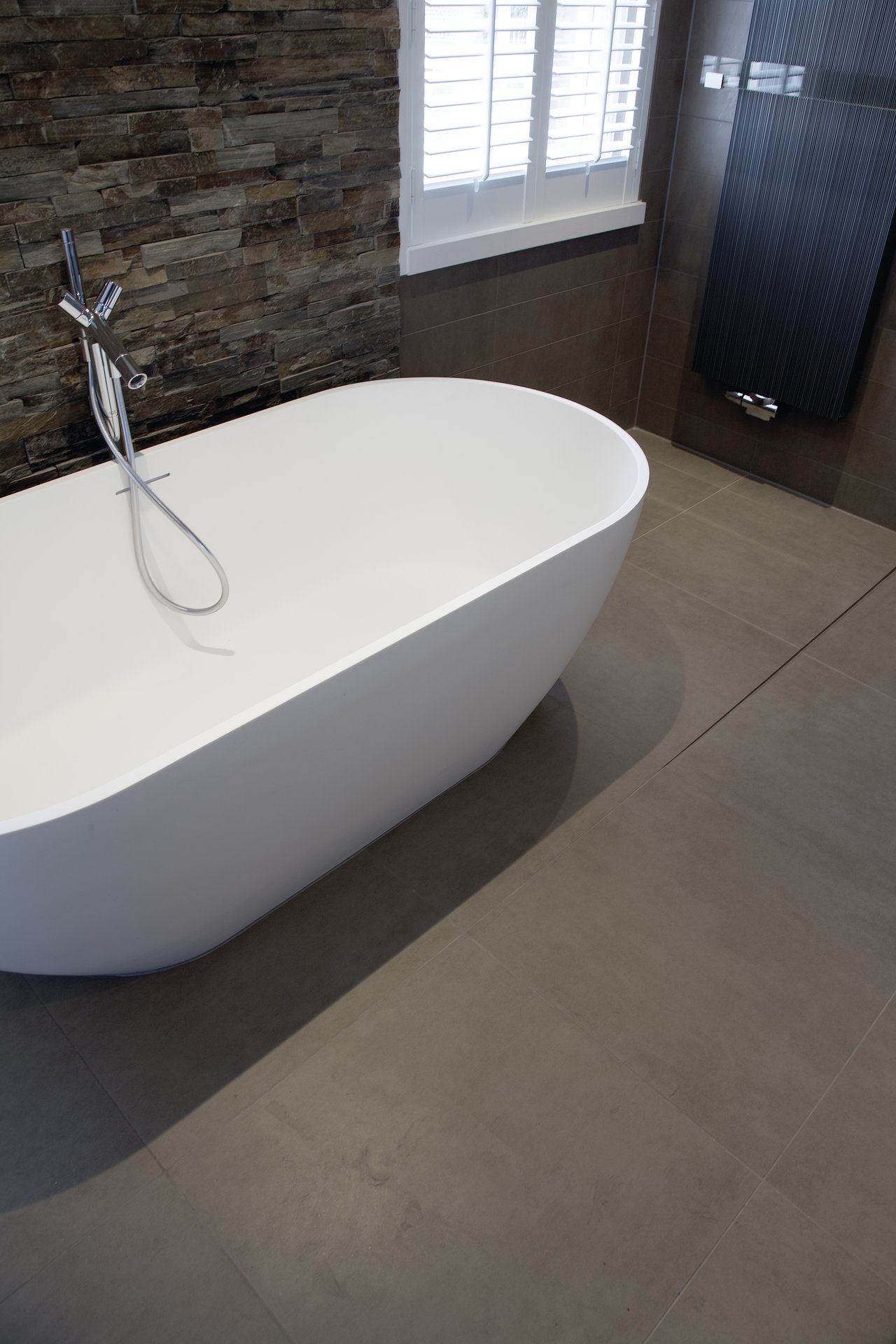 Premium anthracite floor and stone-effect wall tiles in a modern bathroom.