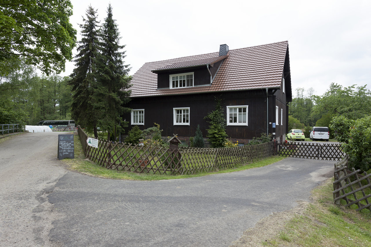 Detached house with brown facade, tiled roof, and well-kept front garden.