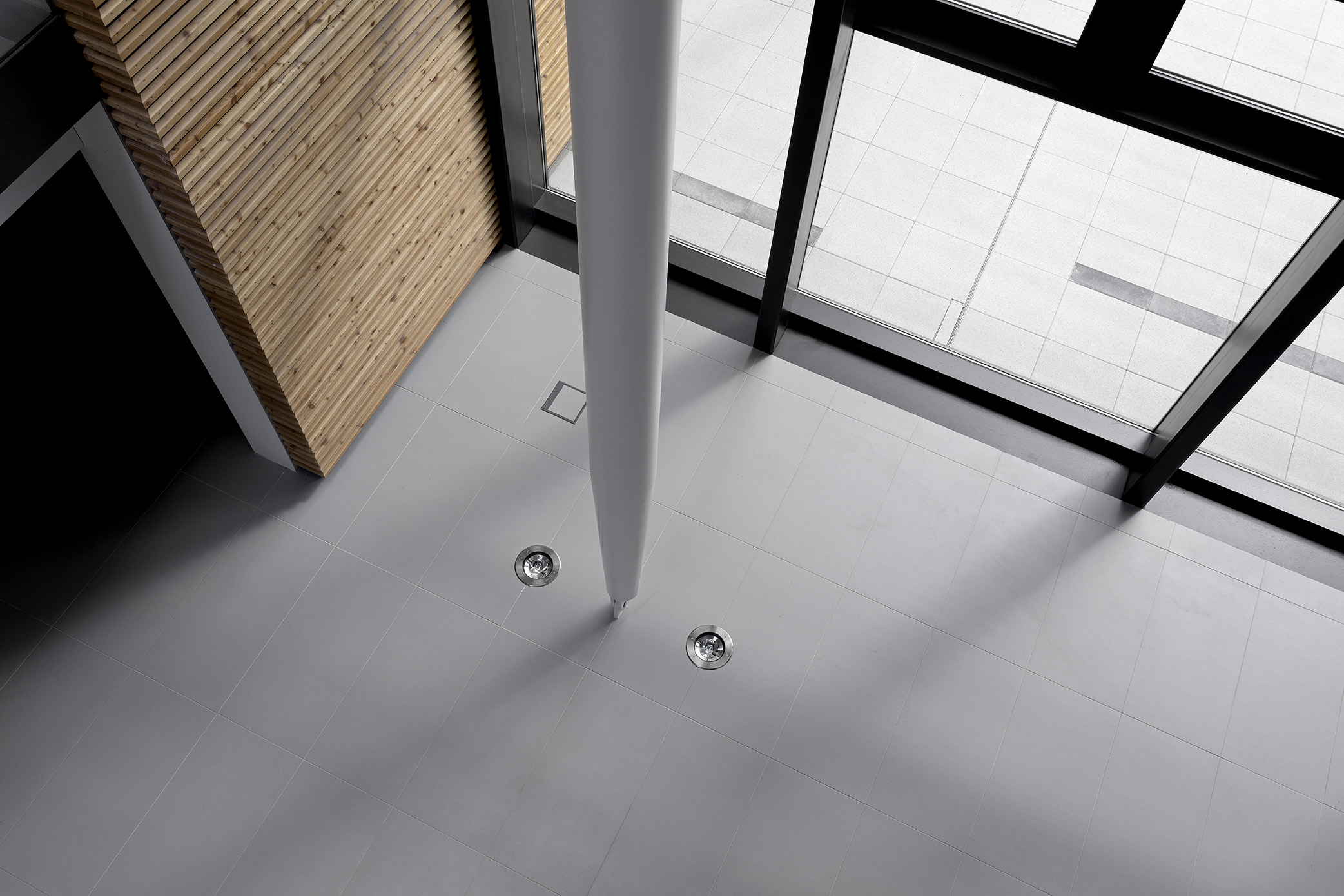 Elegant light grey indoor floor tiles with a column and a view of outdoor tiles.