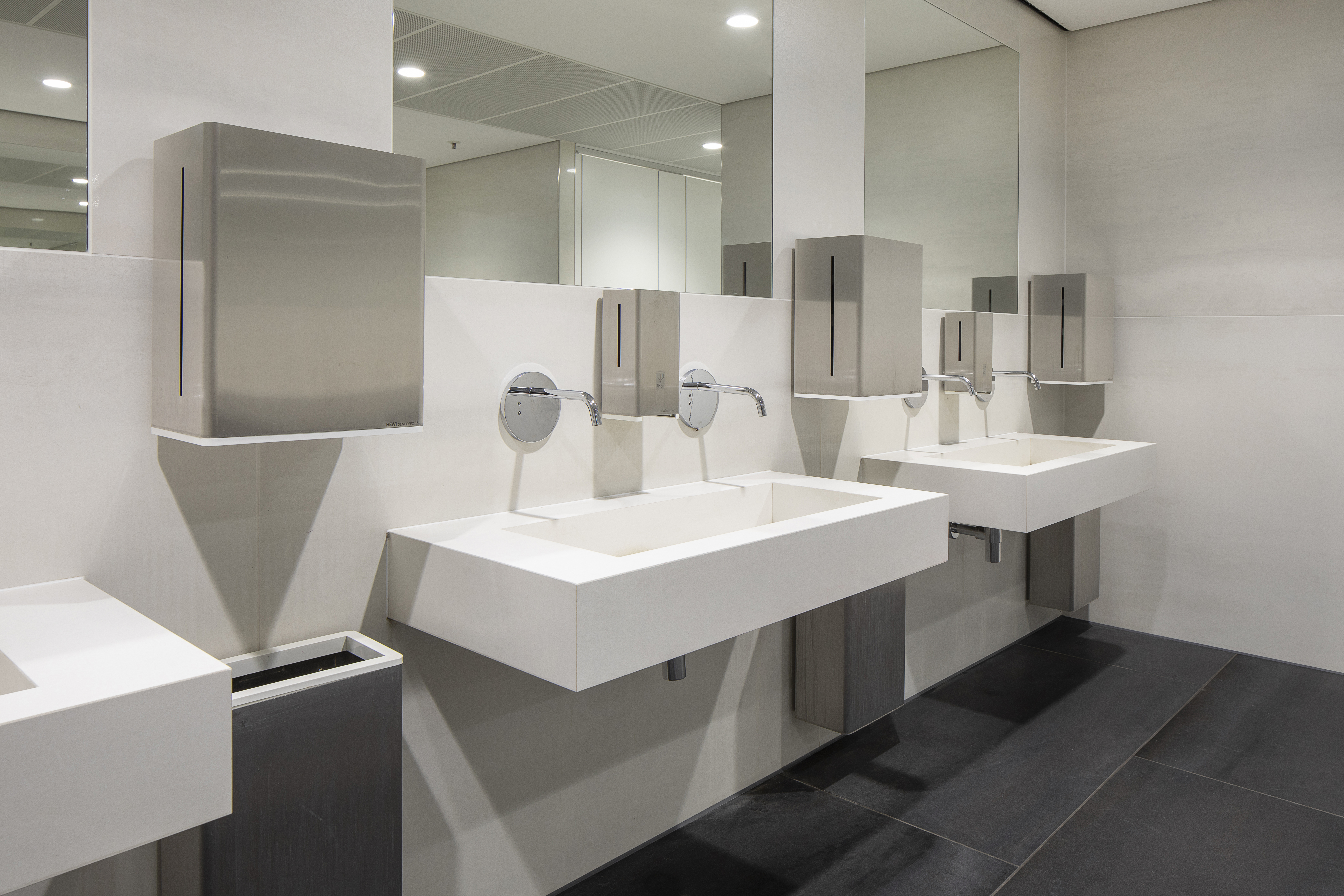 Modern bathrooms with dark floor and light wall tiles.