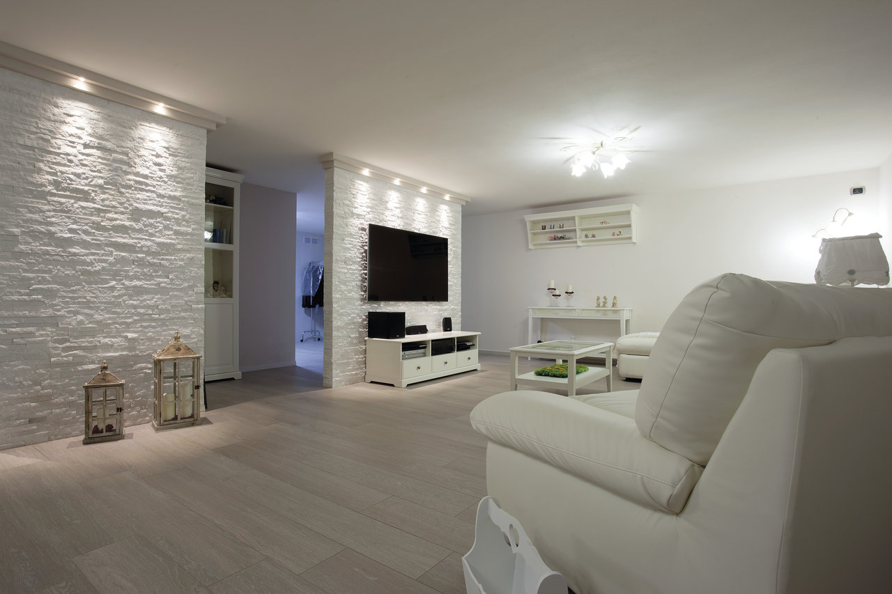Modern living room with light floor tiles and textured wall tiles.