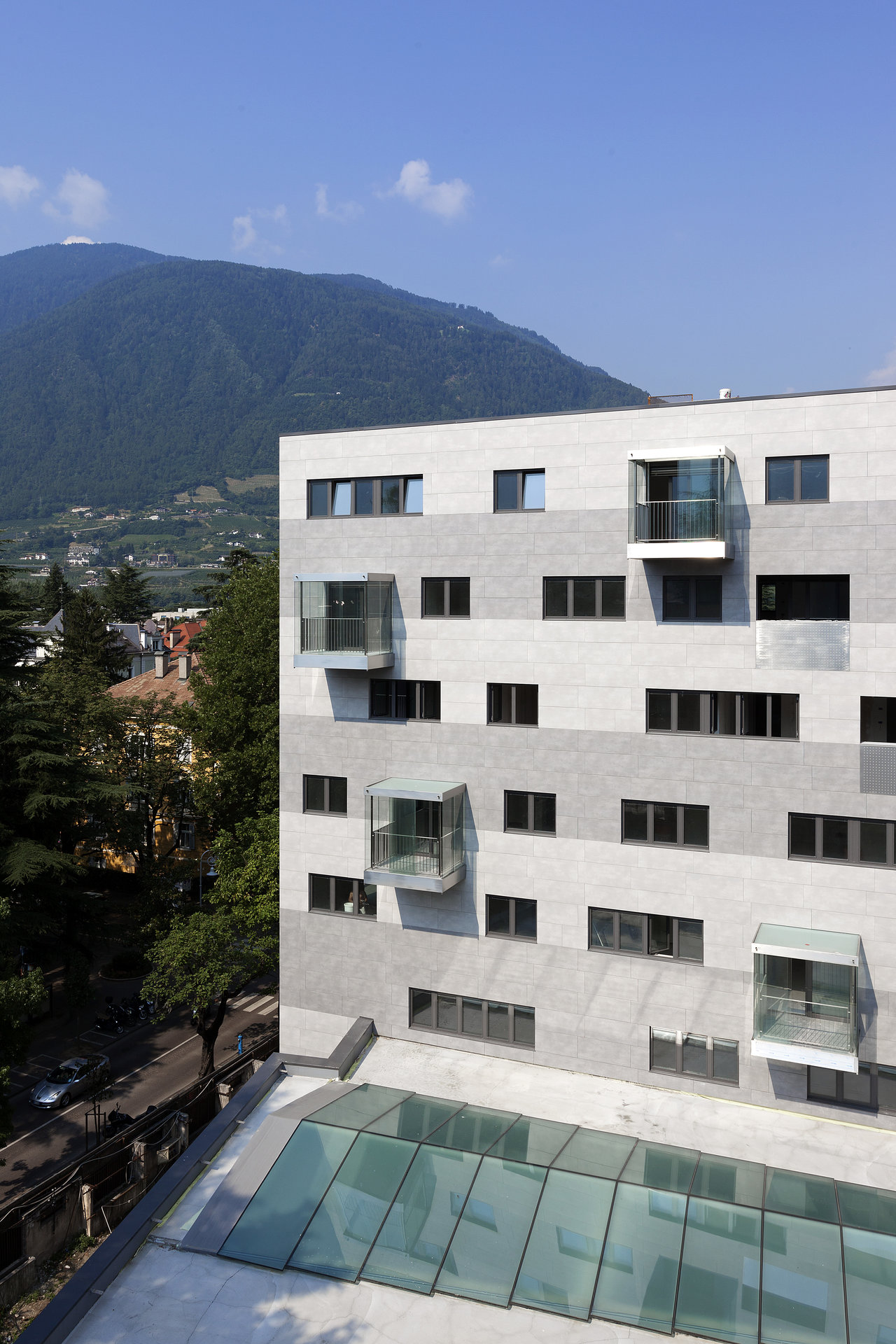 Modern building facade with horizontal stripes in shades of grey and glass balconies.