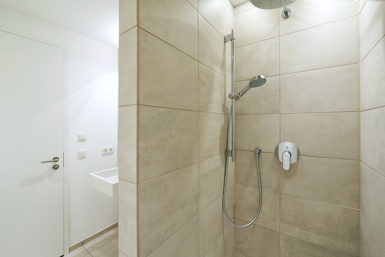 High-quality light beige tiles in a modern shower area.