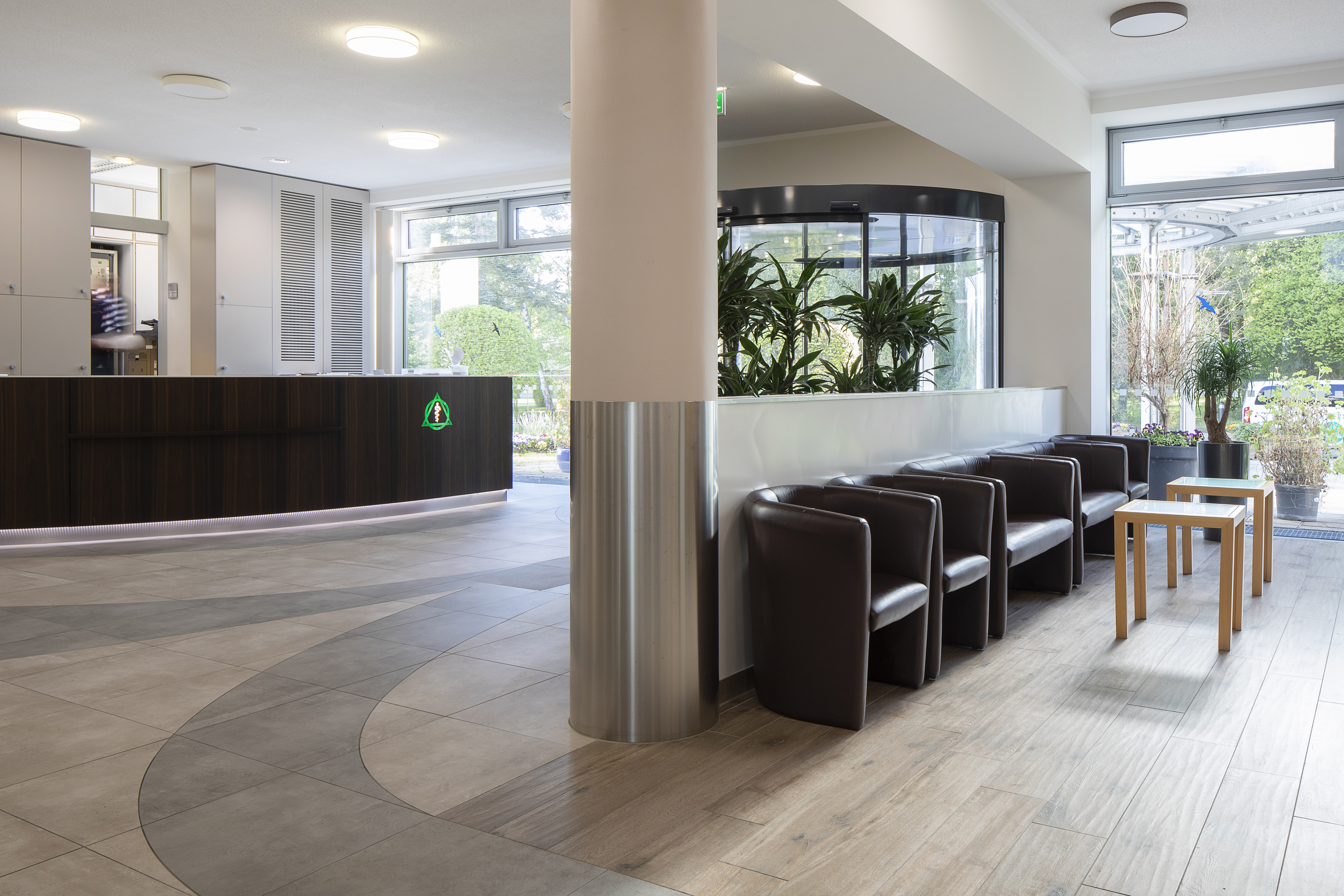 Modern reception area with high-quality floor tiles in light natural stone look and curved pattern.