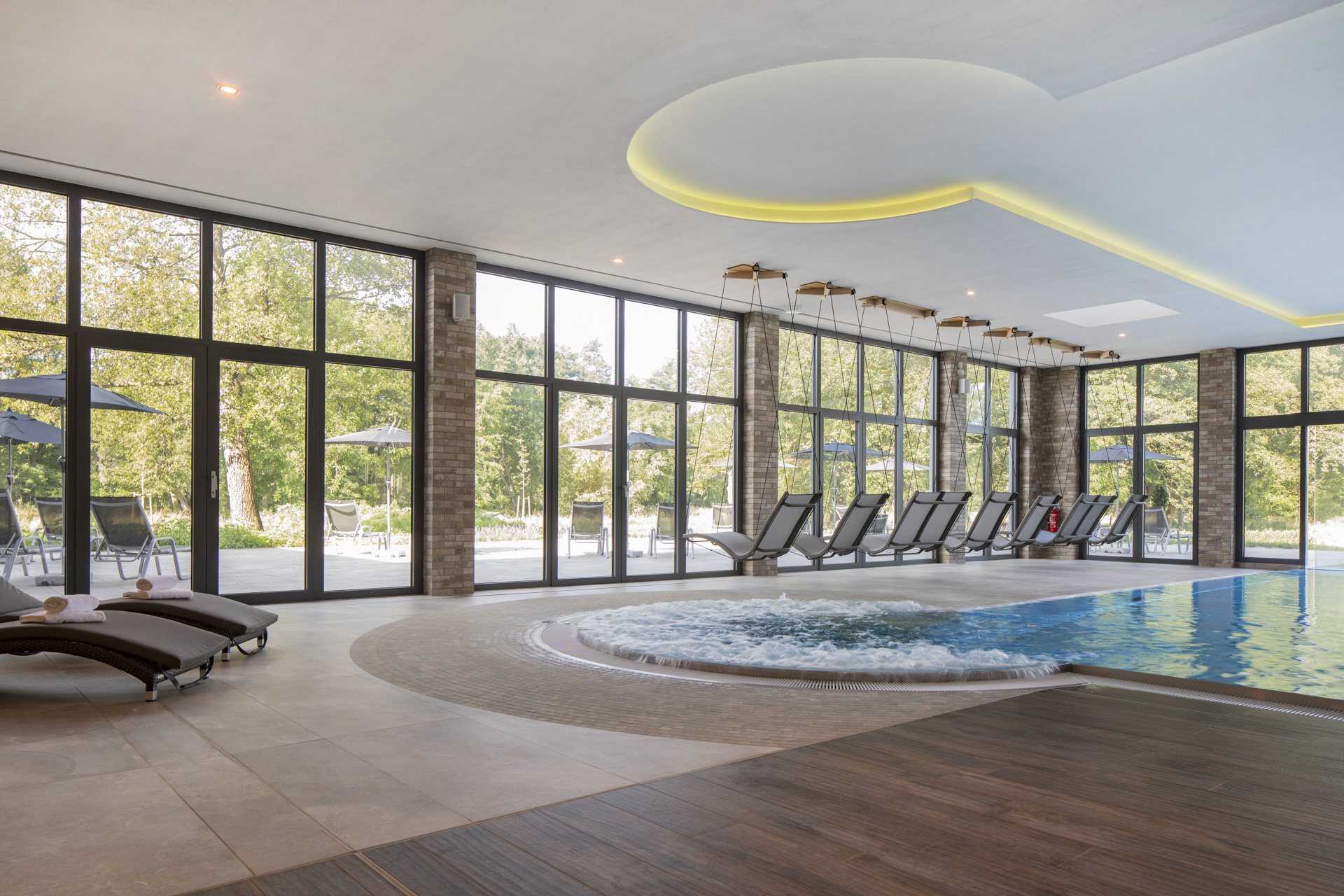 Luxurious indoor pool area with stylish Porcelaingres and Schöner Wohnen tiles, whirlpool, and green views.