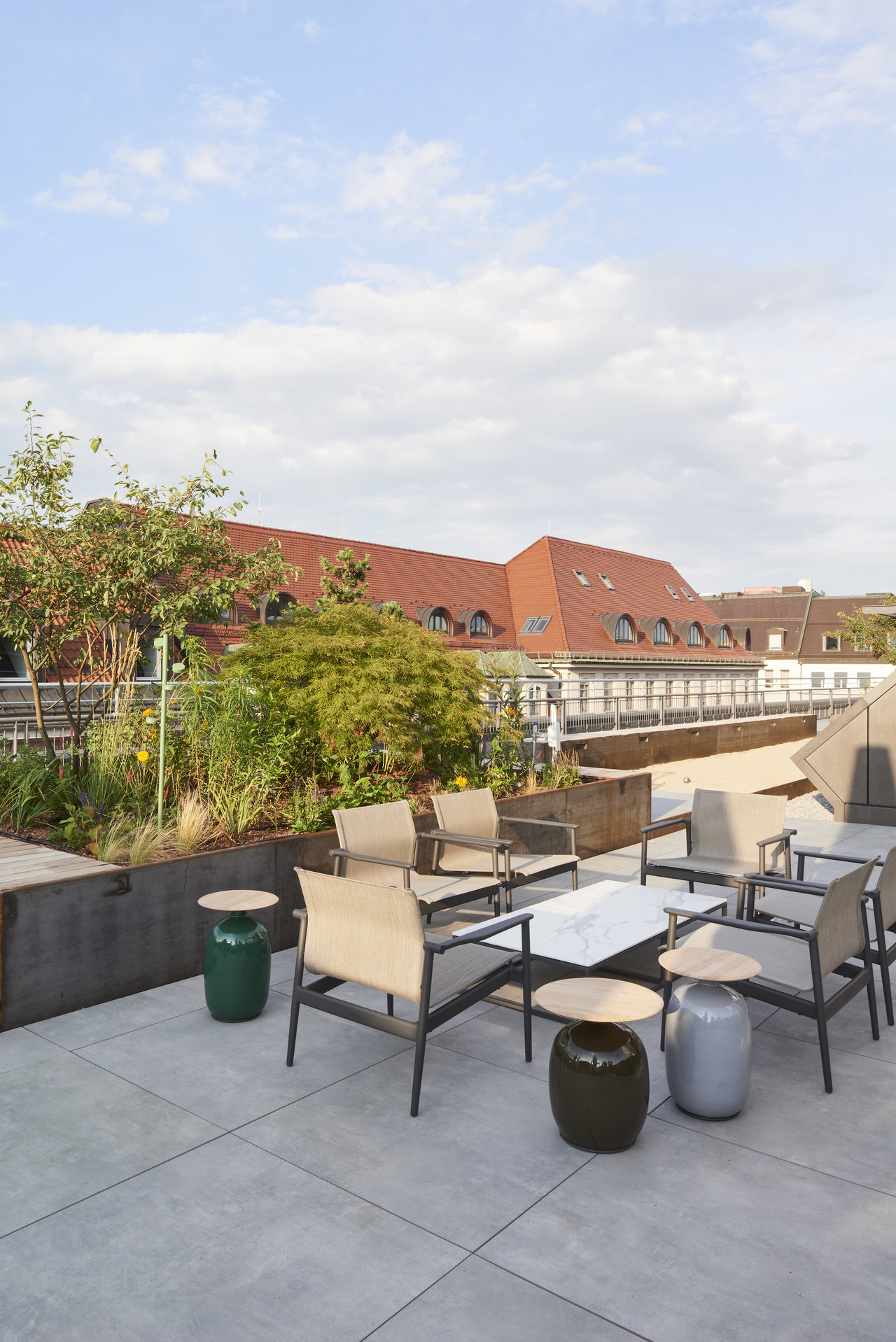 Large-format outdoor tiles on a modern roof terrace with plants and a seating area.