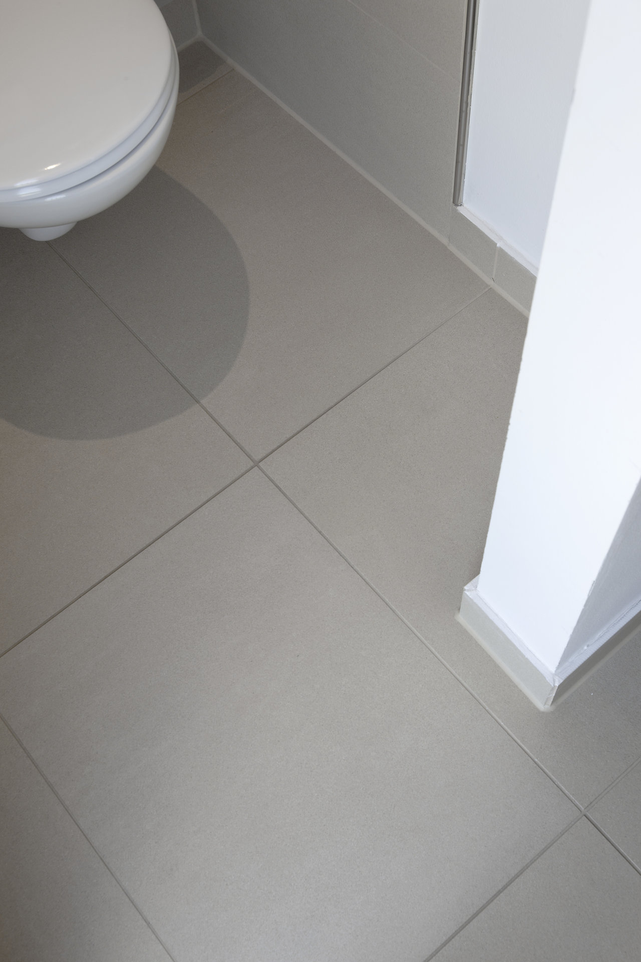 Textured porcelain stoneware floor tiles in light grey-beige for bathroom and WC.
