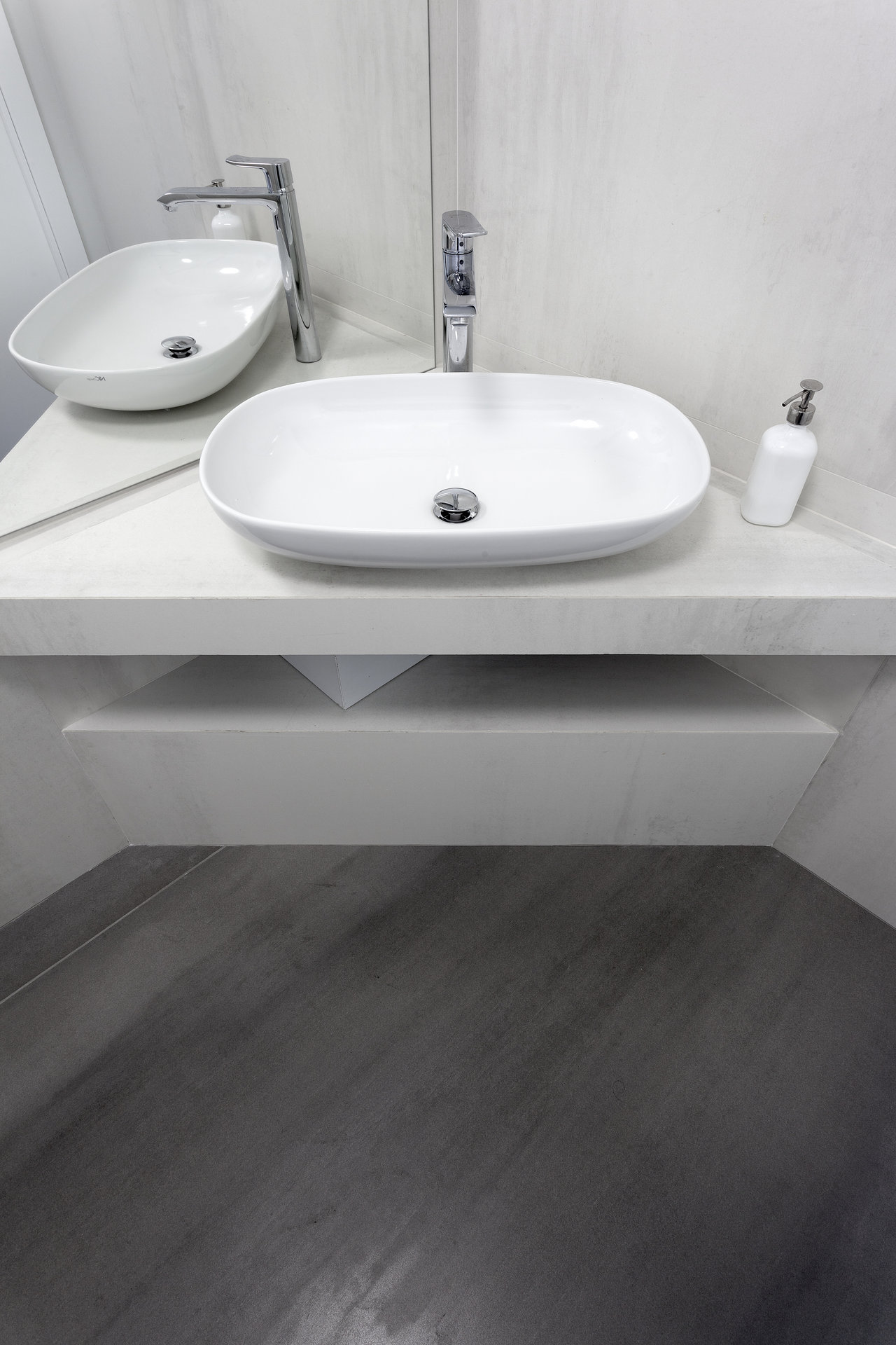 Dark grey concrete-look floor tiles in a modern bathroom with light walls.