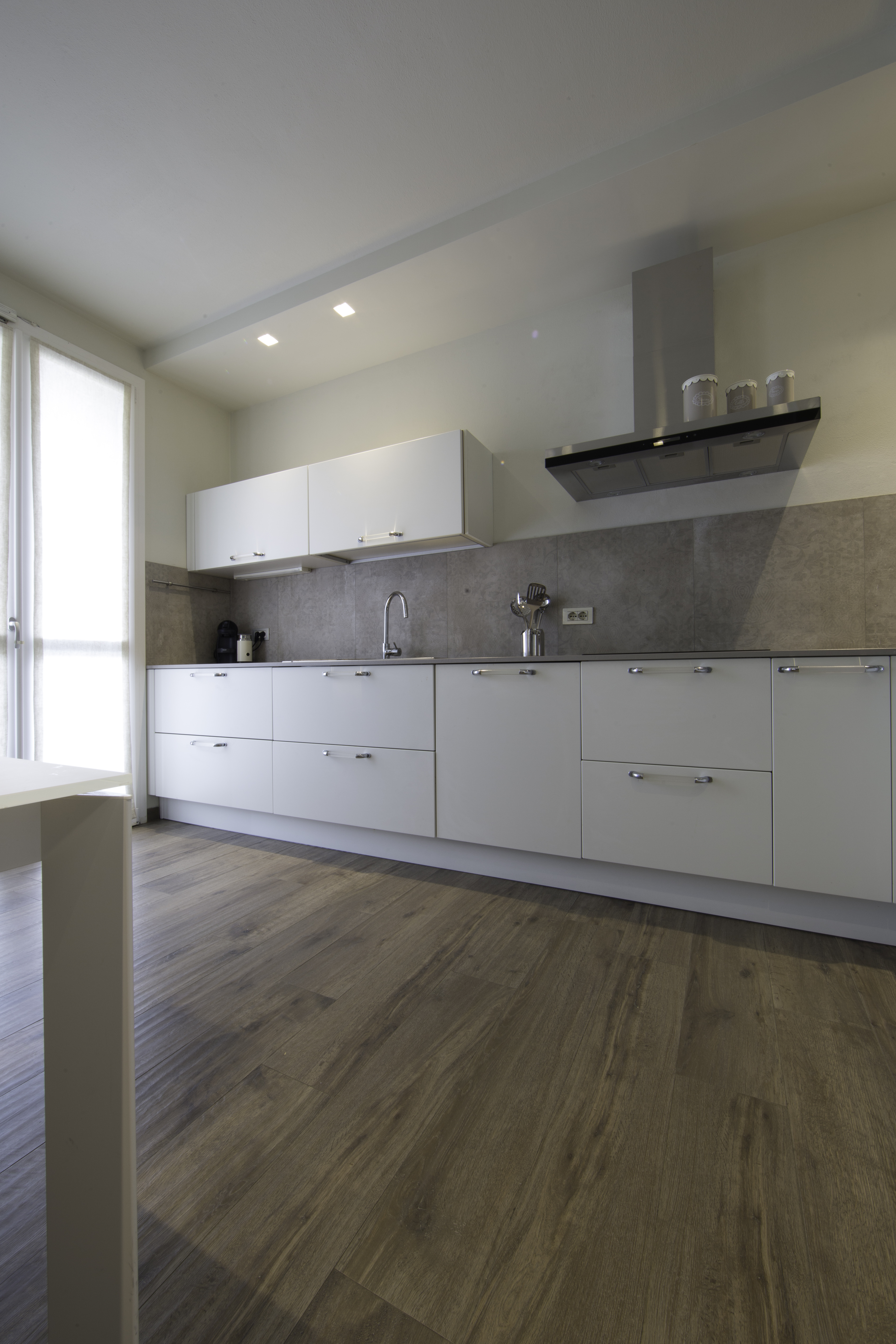 Bright, modern kitchen with wood-look floor tiles and grey wall tiles.