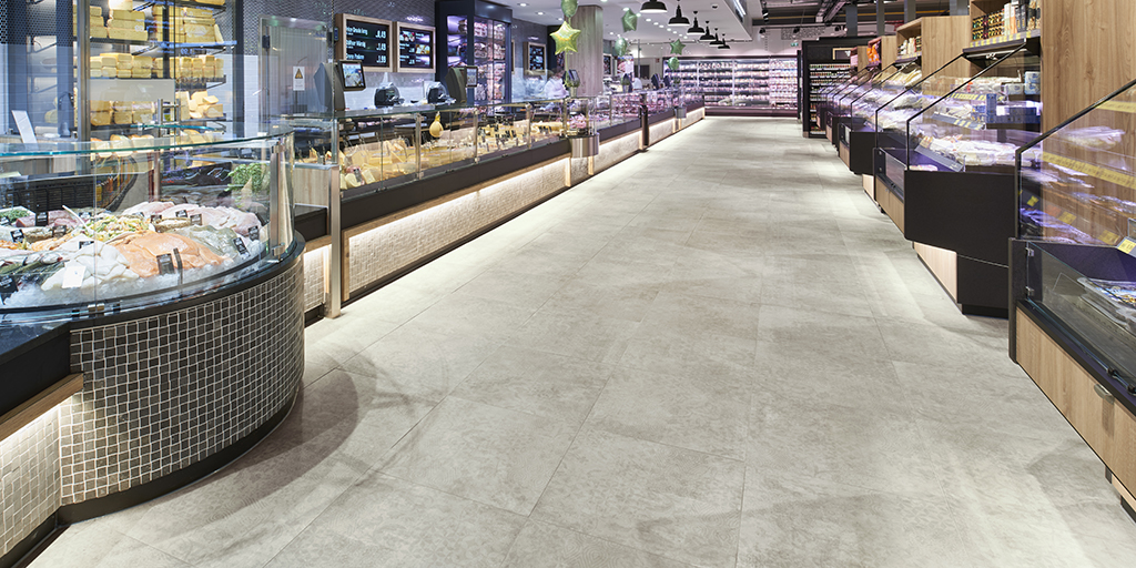 Robust, light grey large format tiles in a modern supermarket.