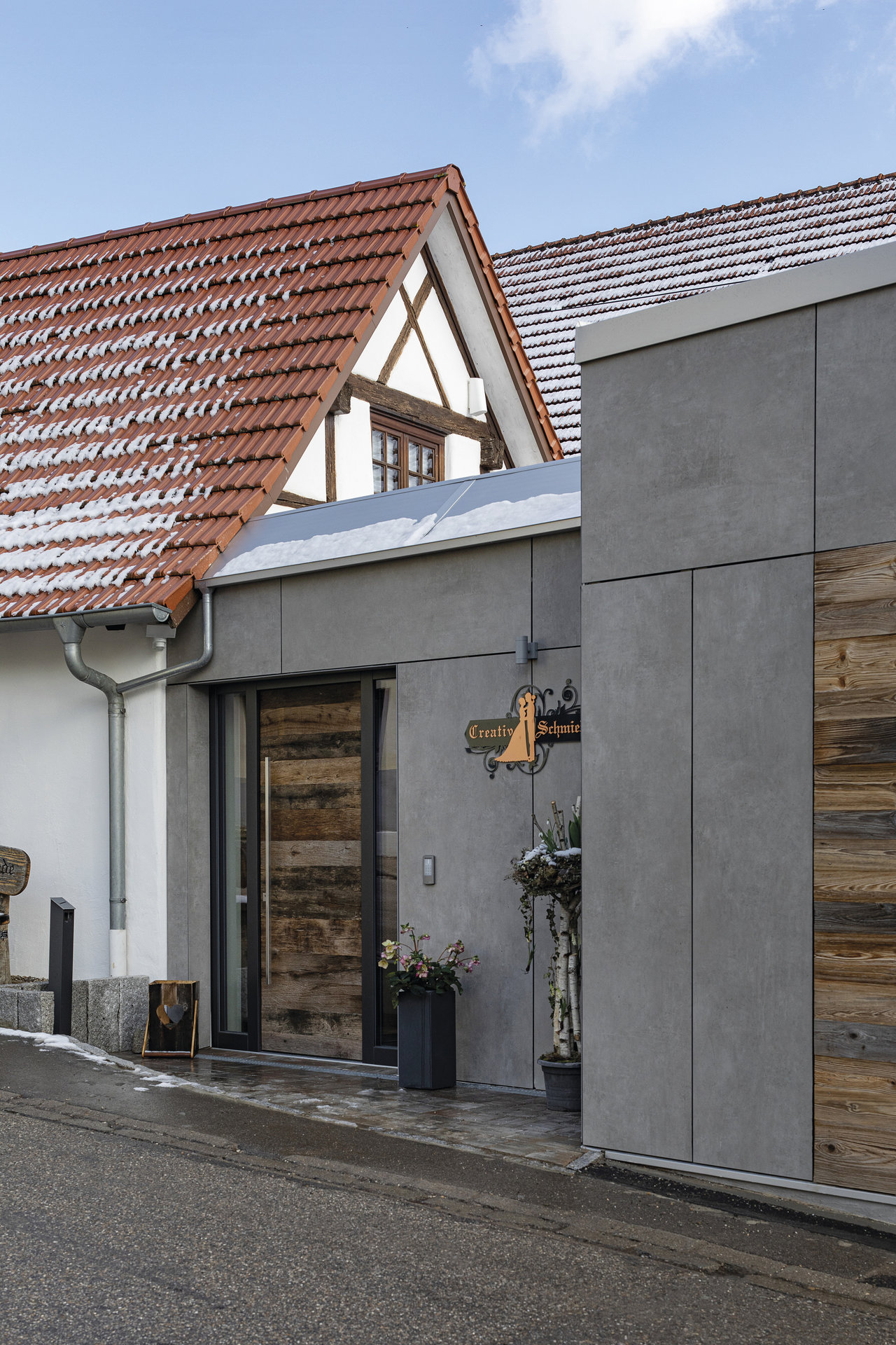 Modern facade with large-format grey tiles and wood cladding.