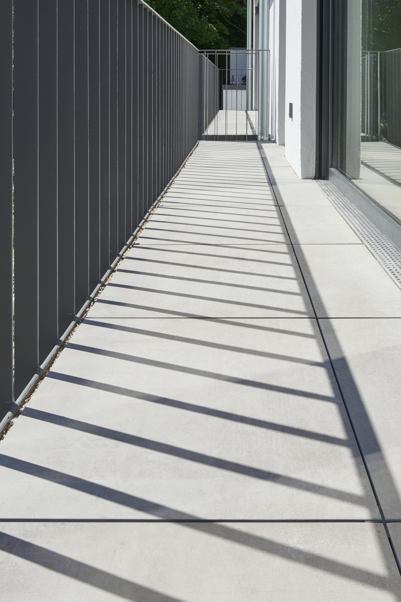 Light outdoor tiles on a modern balcony with elegant shadows.