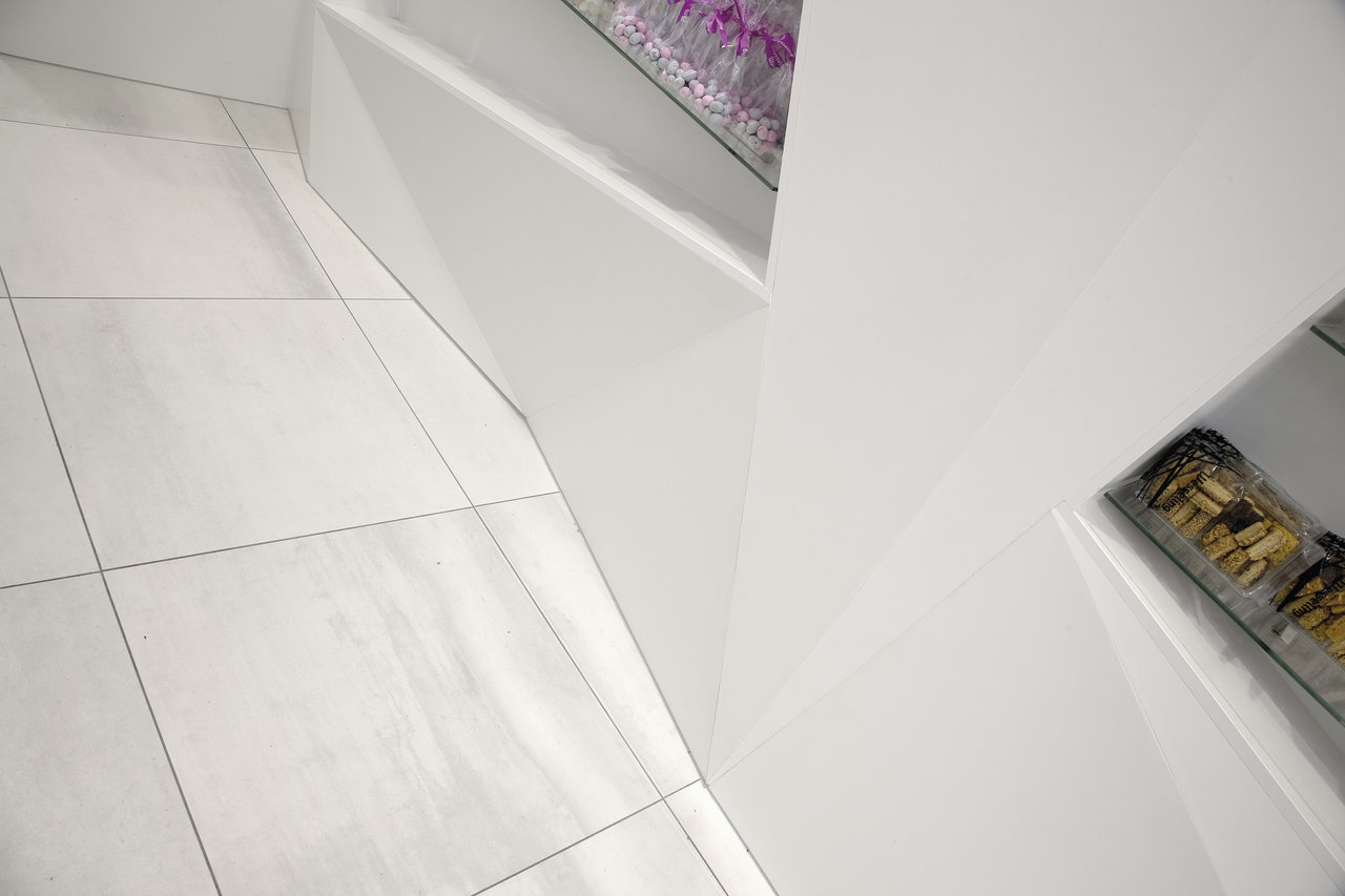 Light, large-format floor tiles with fine texture in a modern setting.
