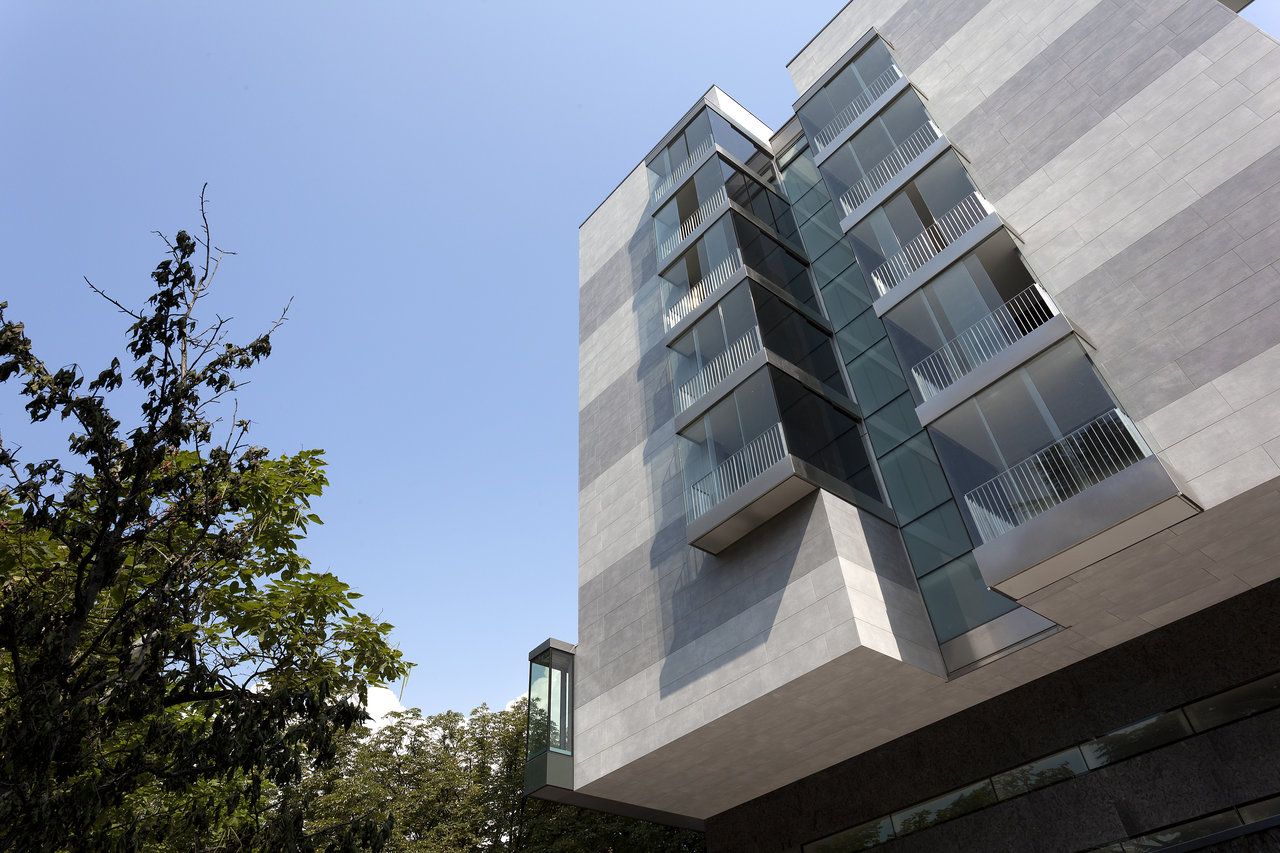 Modern building facade with grey tiles and glass balconies.