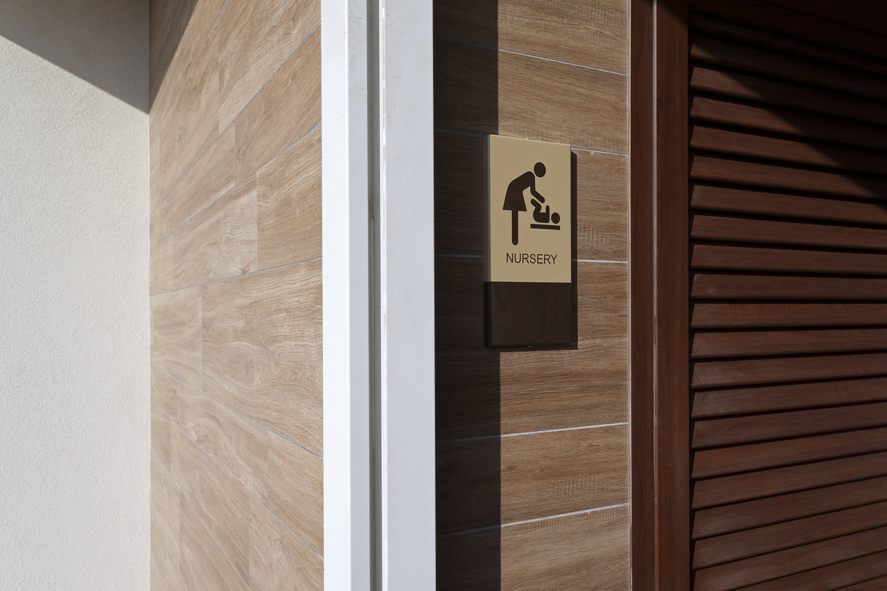 High-quality wood-effect tiles on a wall with a baby changing sign.