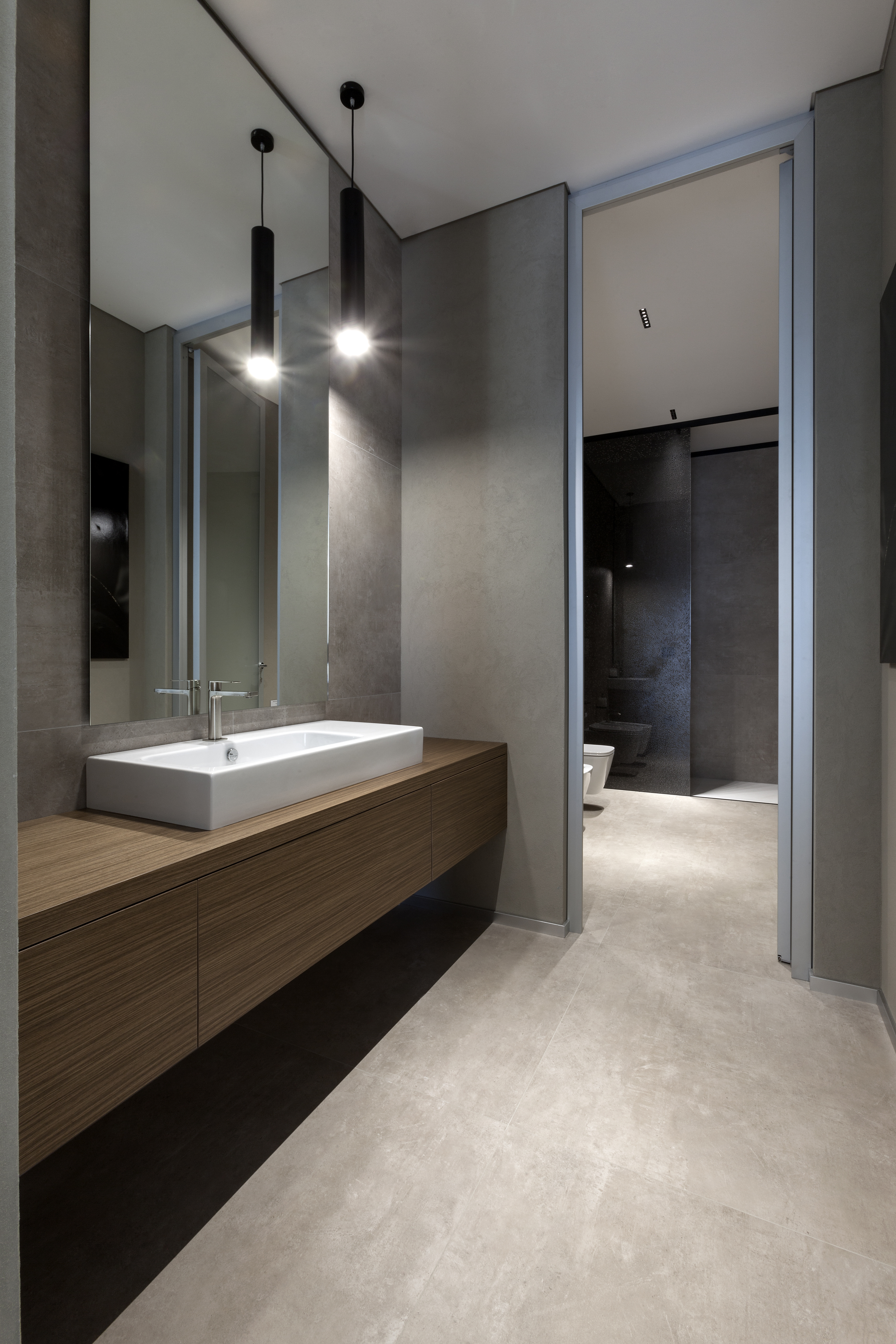 Elegant bathroom with large-format concrete-look tiles and a floating wooden vanity.