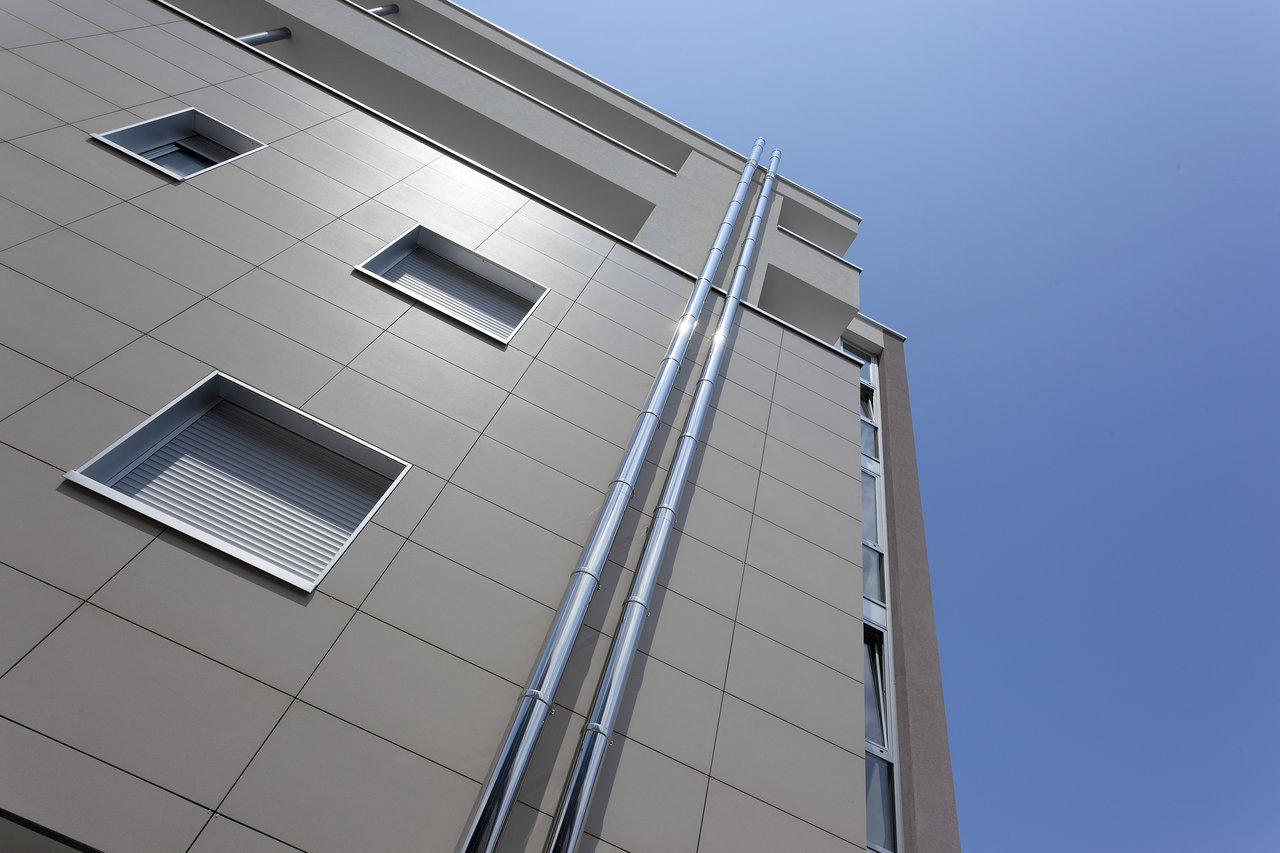 Large, bright facade tiles on a modern building under a blue sky.