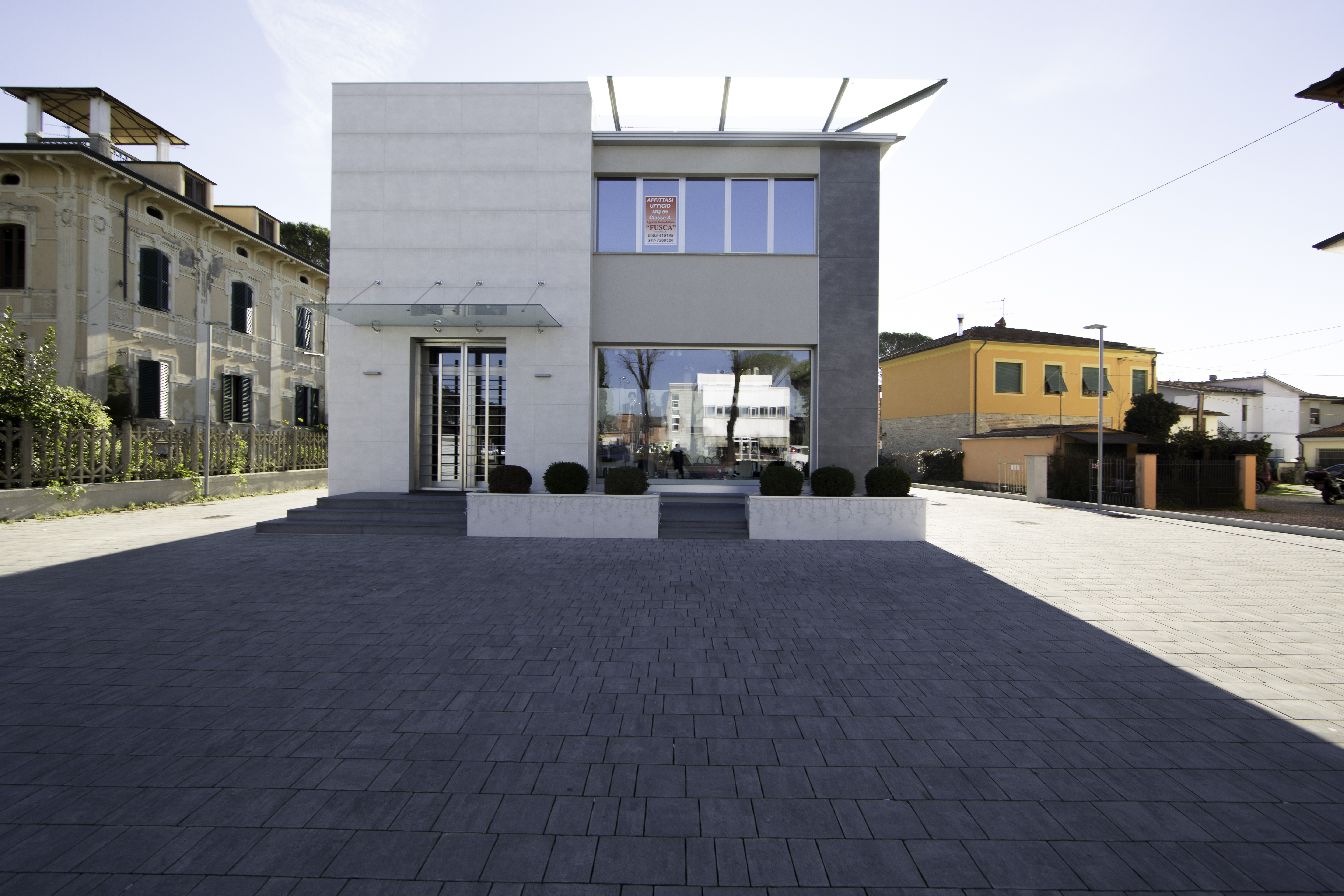 Modern forecourt with dark outdoor tiles in front of an elegant building.
