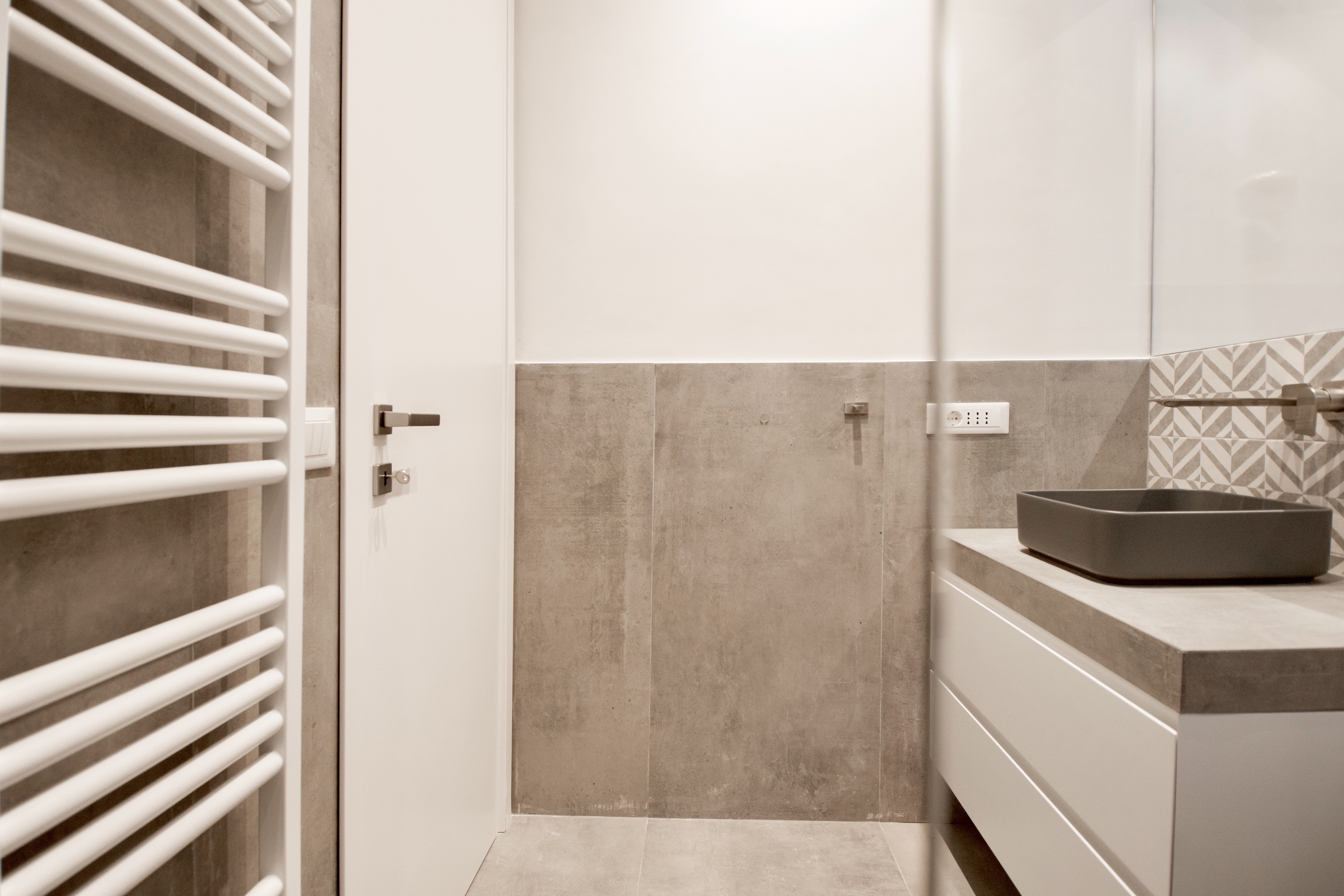 High-quality tiles in a modern bathroom: large-format wall and floor tiles, accent tiles, and washbasin.