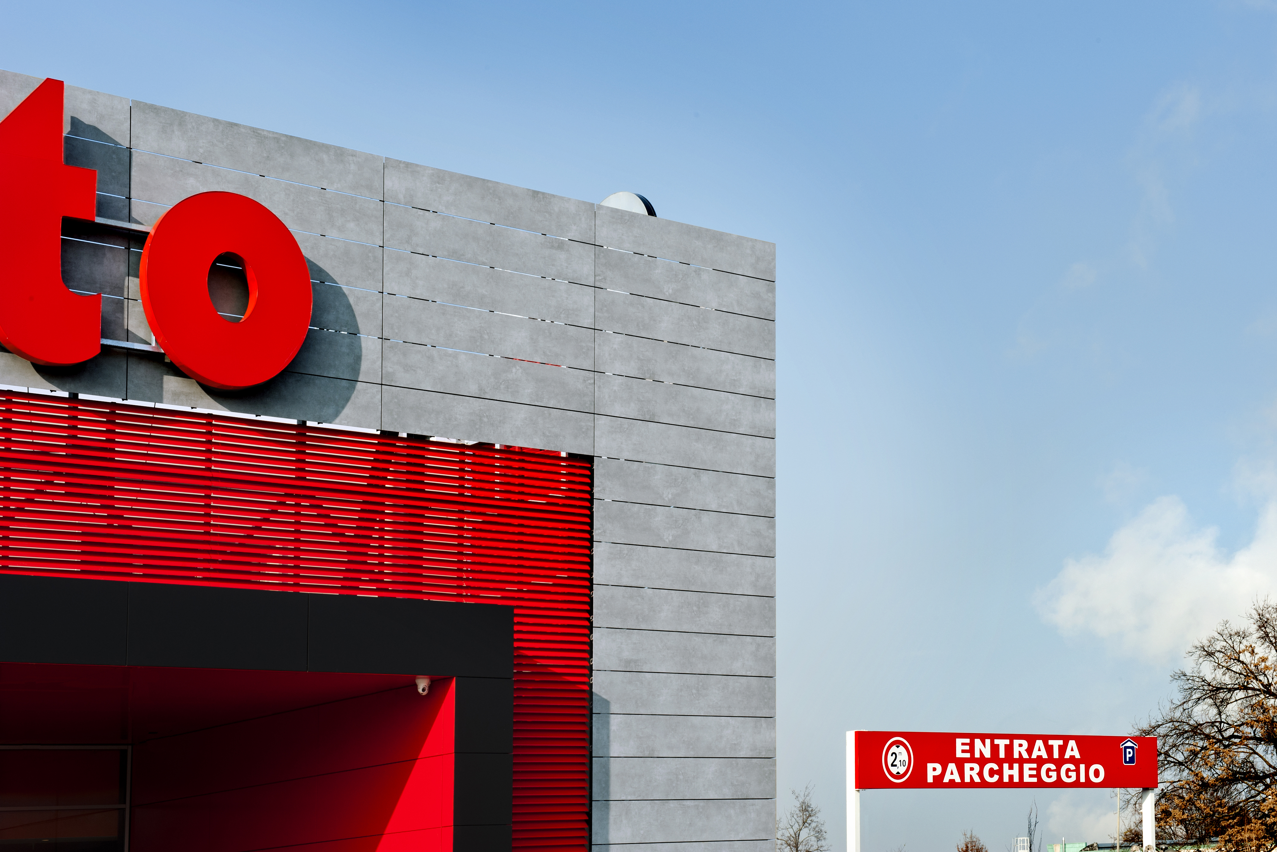 Modern facade with large-format grey tiles and red accents.