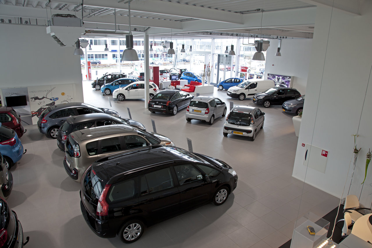 Large, bright showroom with cars on modern flooring.