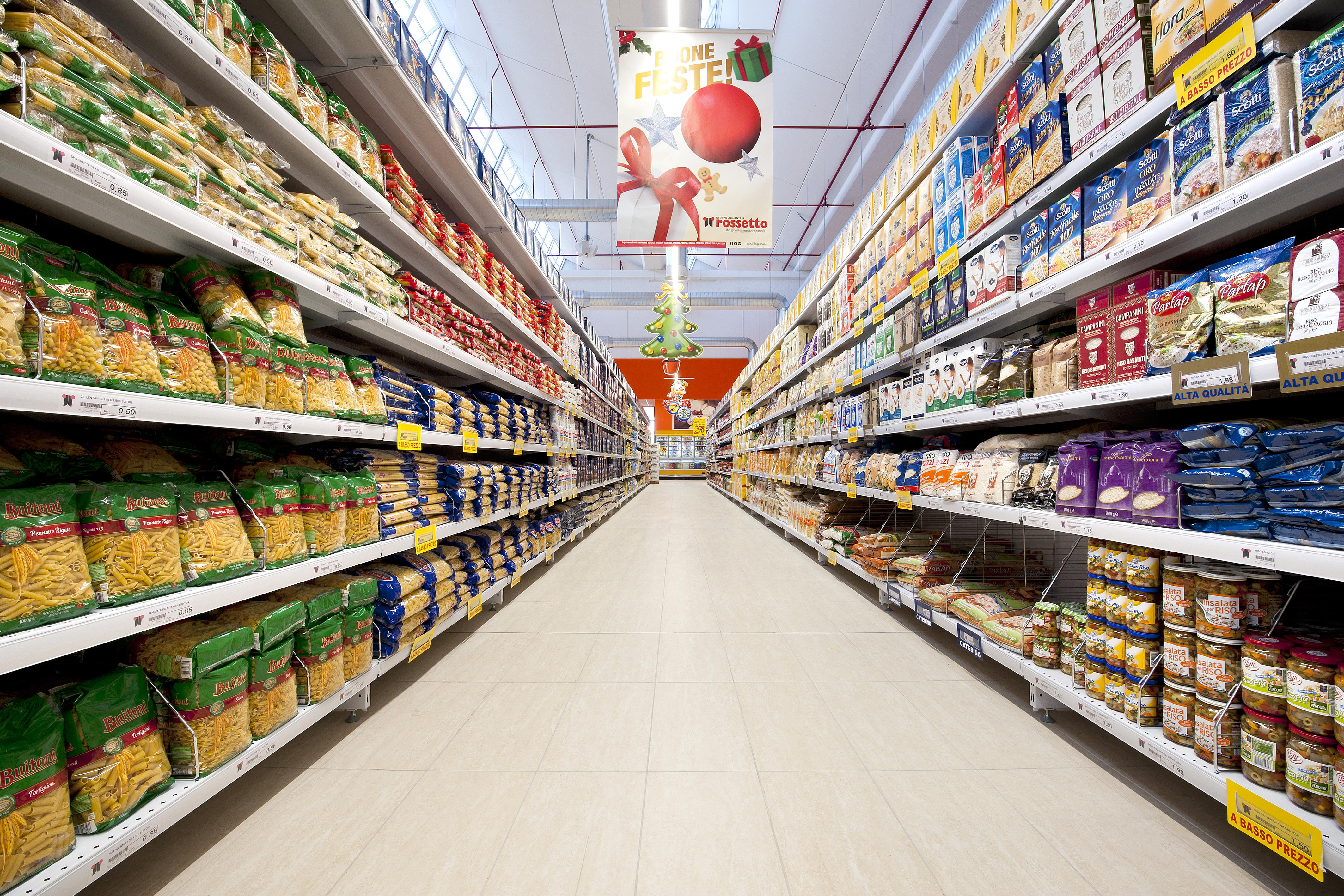 Supermarket aisle with full shelves of groceries and Christmas decorations.