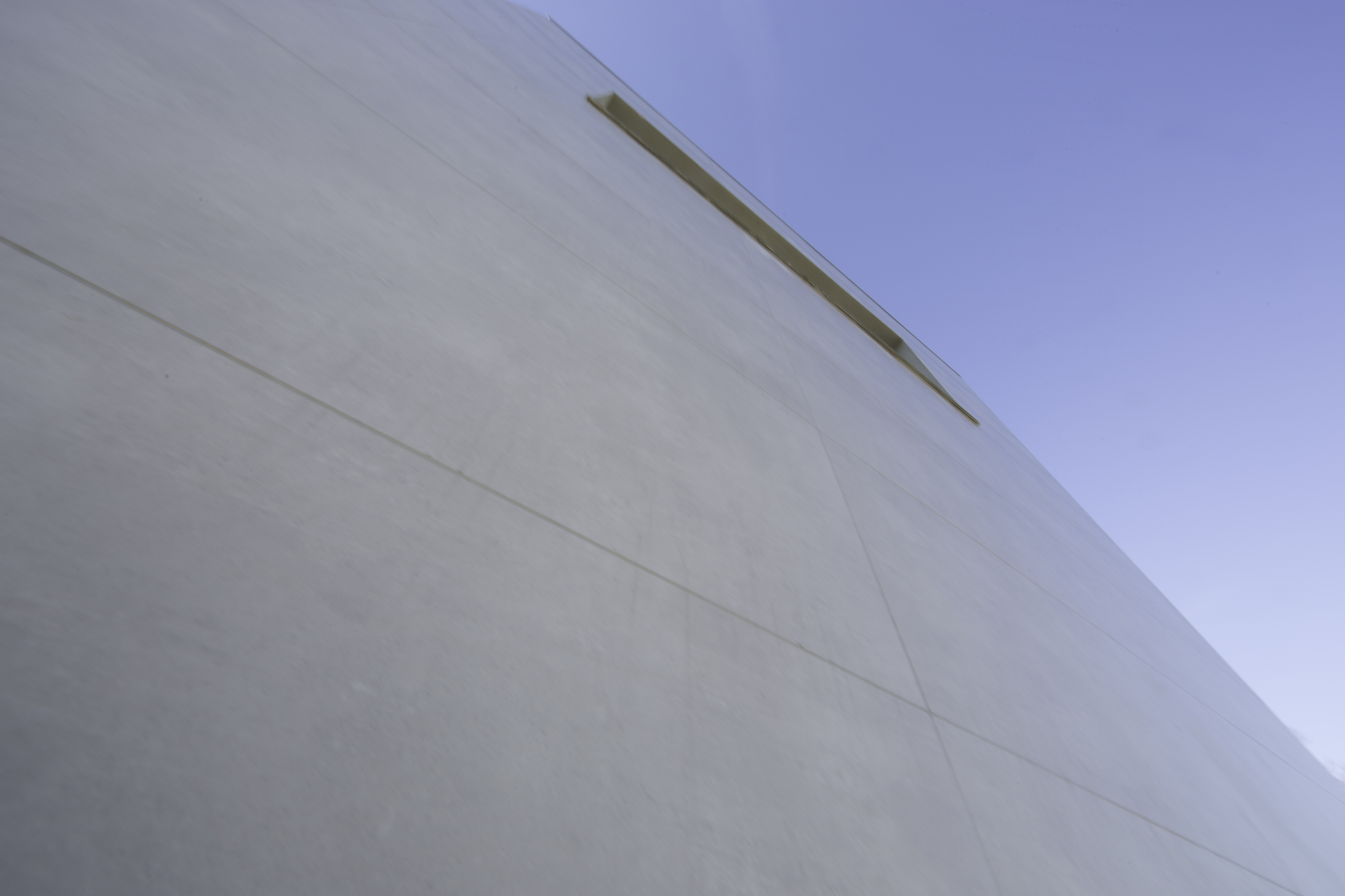 High-quality, large-format tiles on a modern facade under a blue sky.