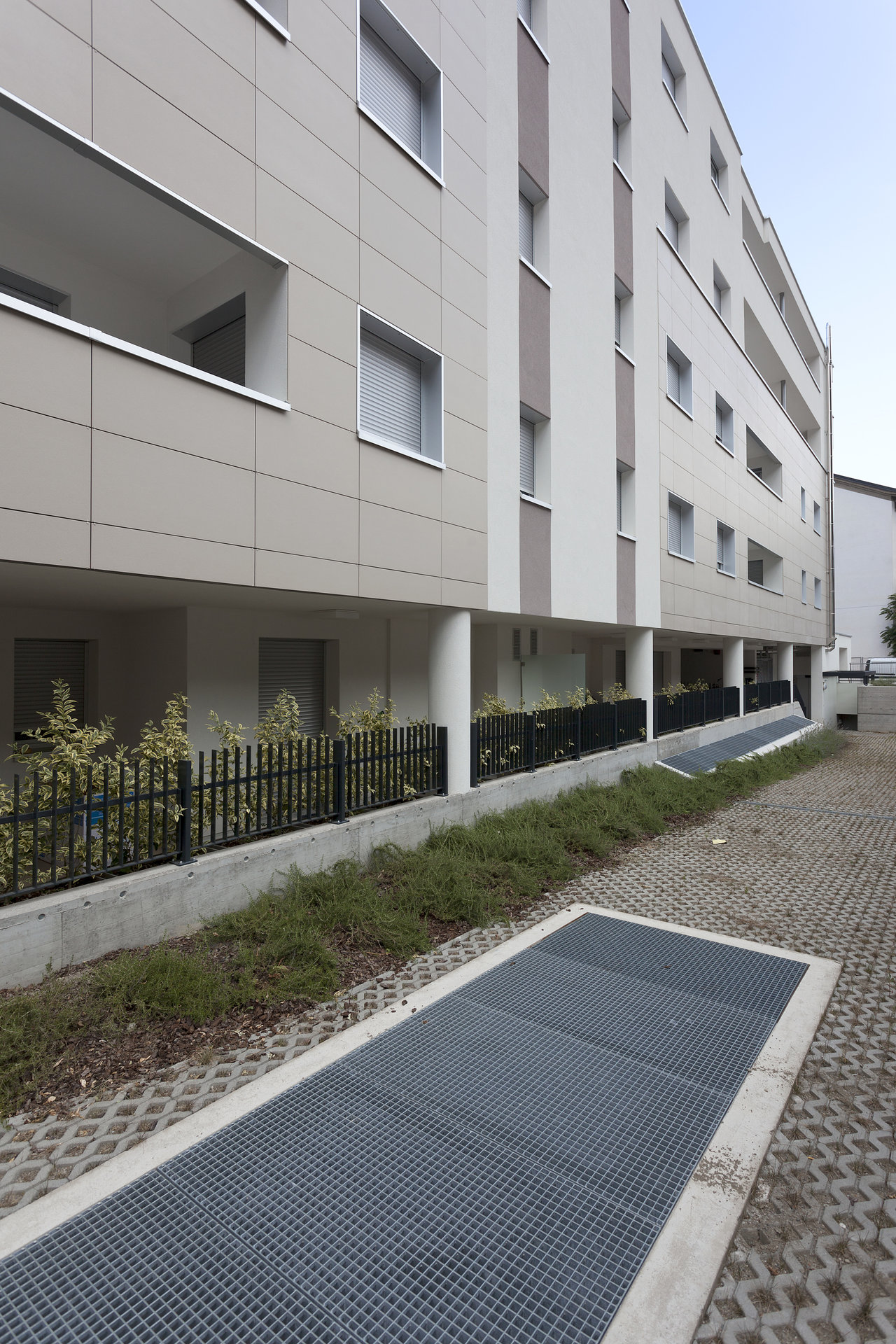 High-quality outdoor area with grass pavers and modern facade made of large-format tiles.