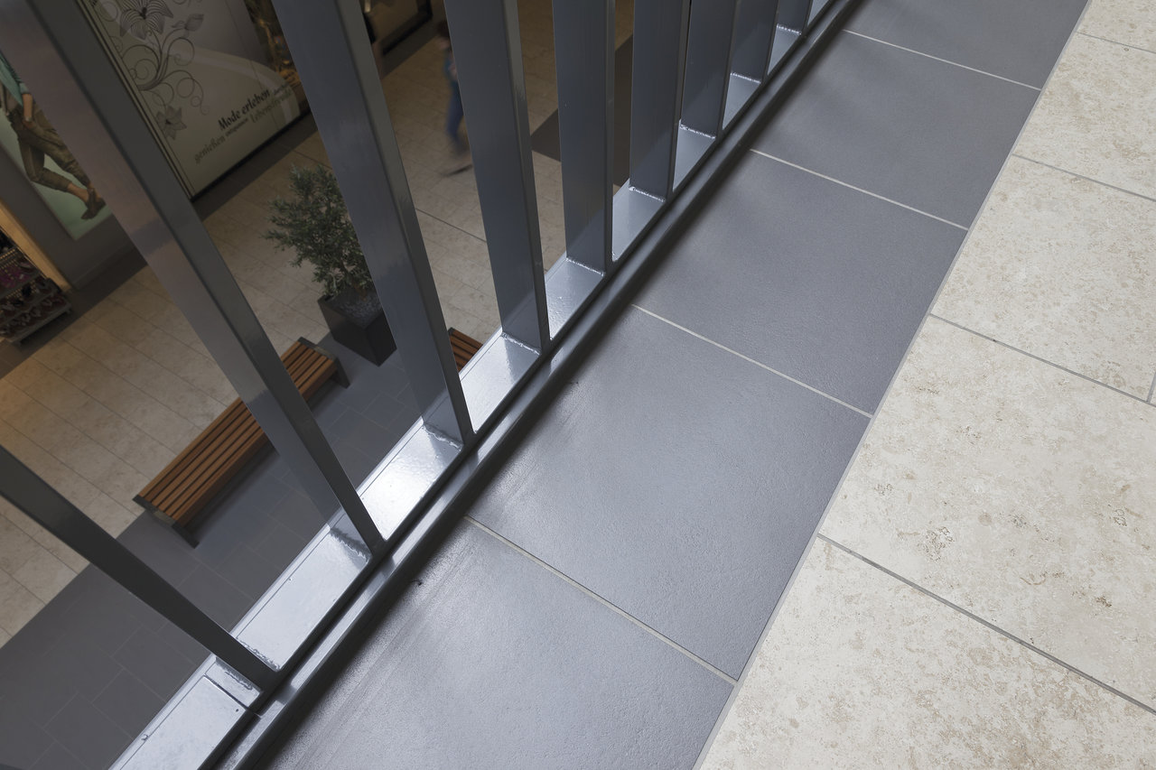 Modern dark grey indoor tiles by a railing.