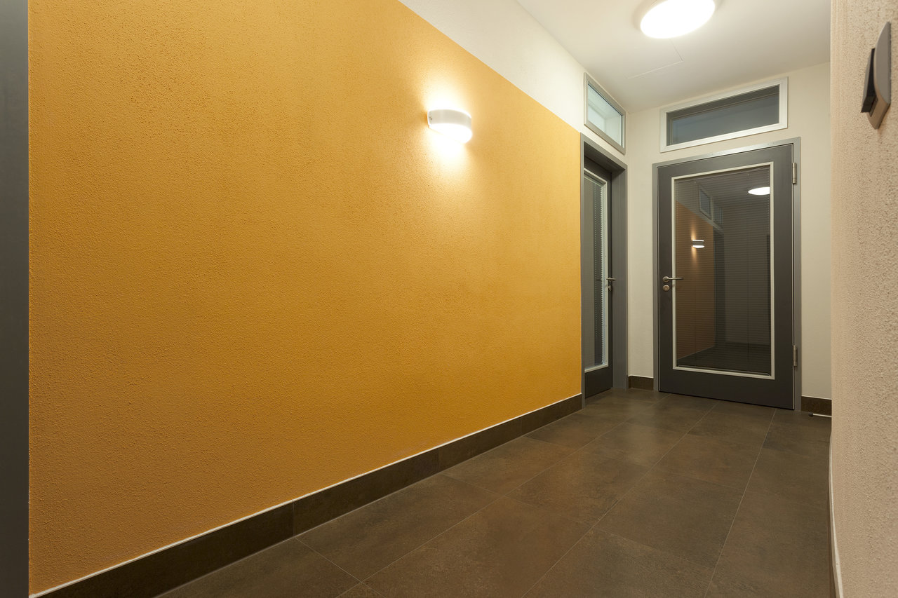 Premium dark floor tiles in a modern hallway with yellow walls.