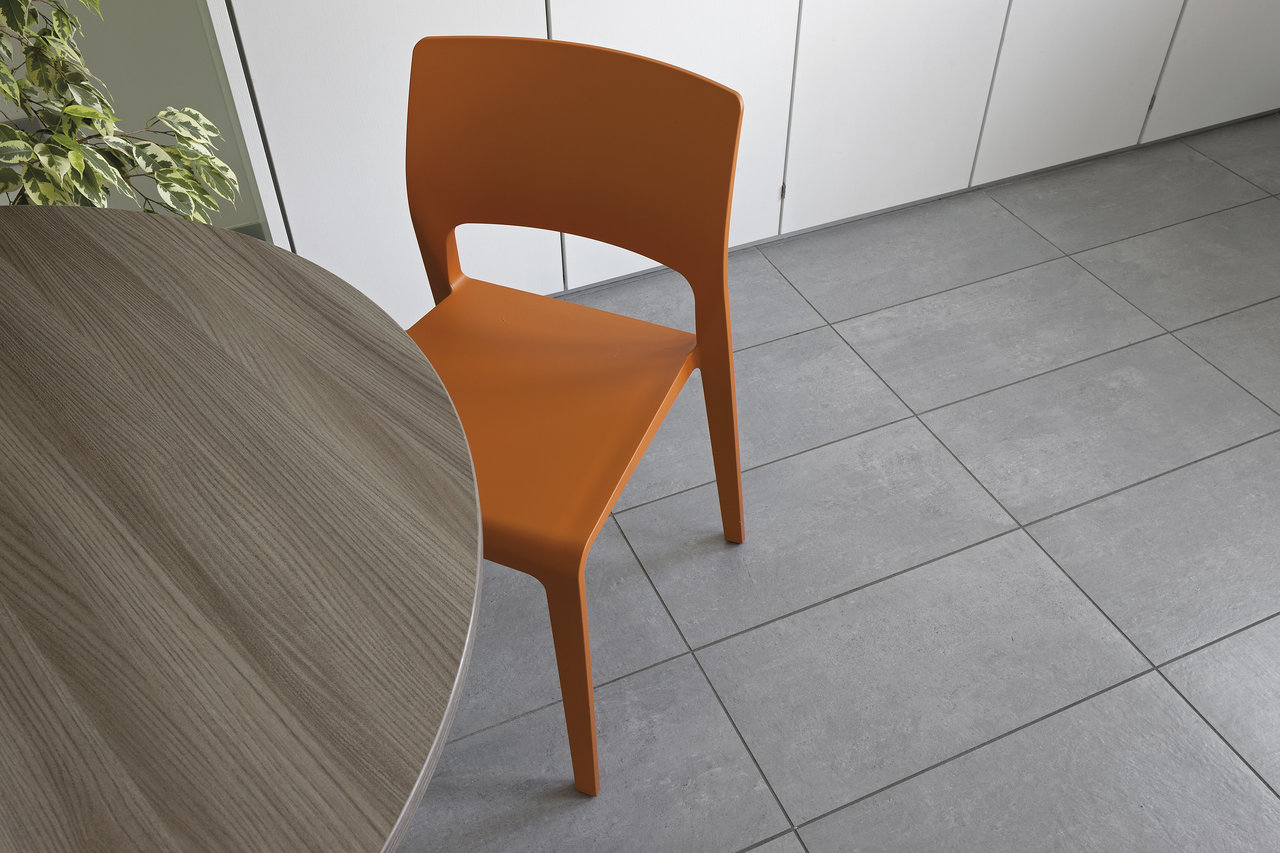 Grey floor tiles in a modern interior with an orange chair.