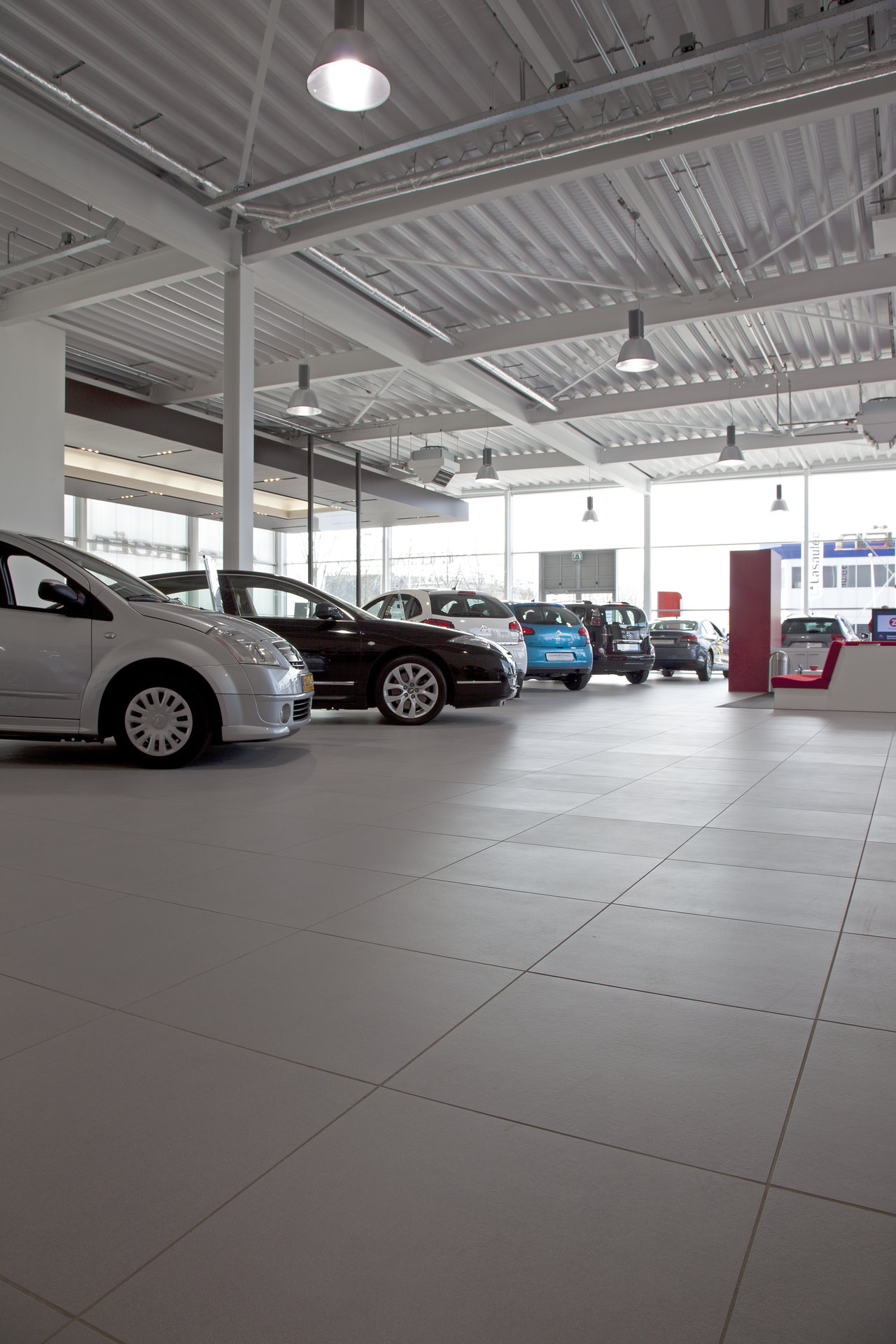 Light, large-format tiles in a car showroom, ideal for high-traffic areas.