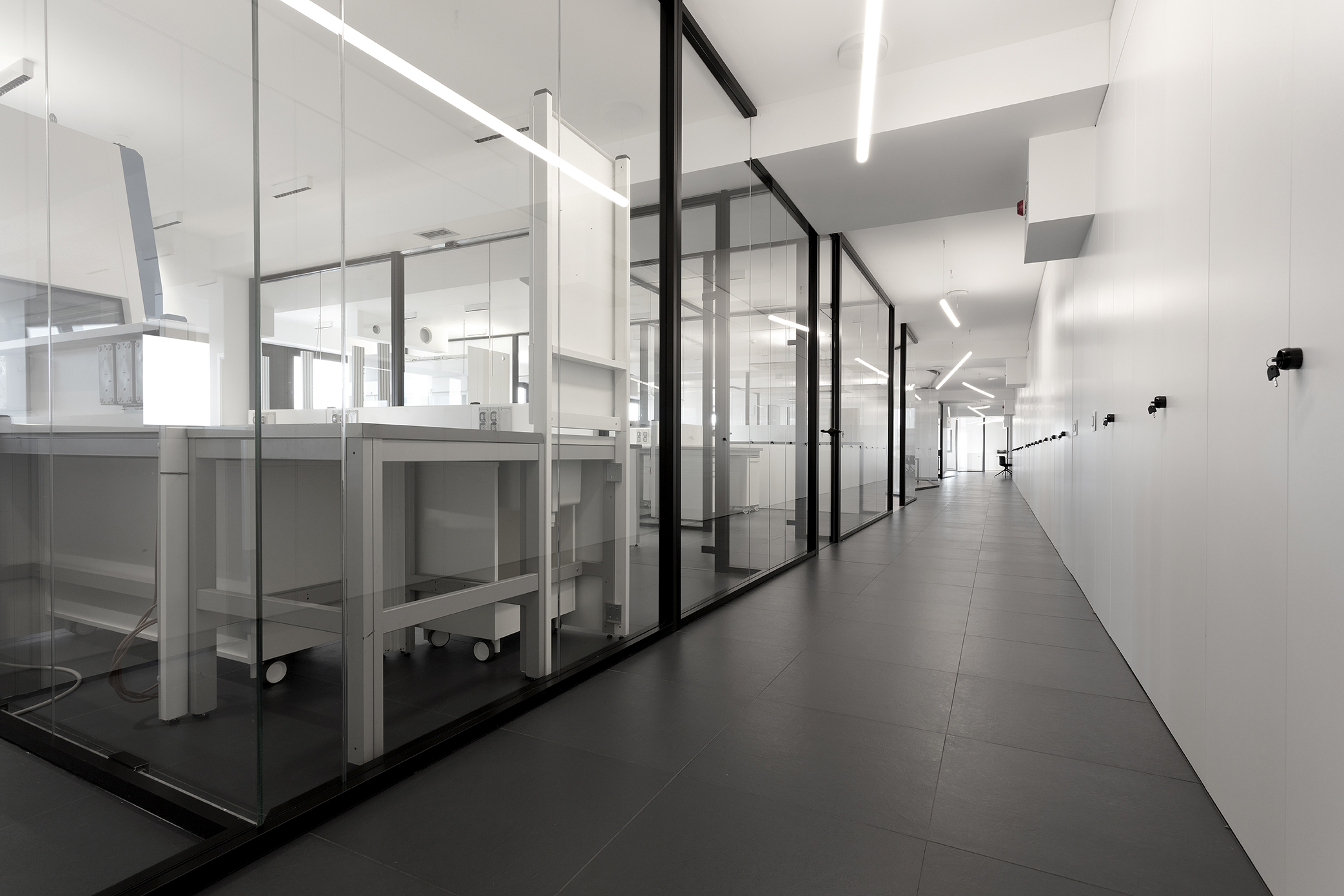 Elegant hallway with large-format, dark tiles and modern glass walls.