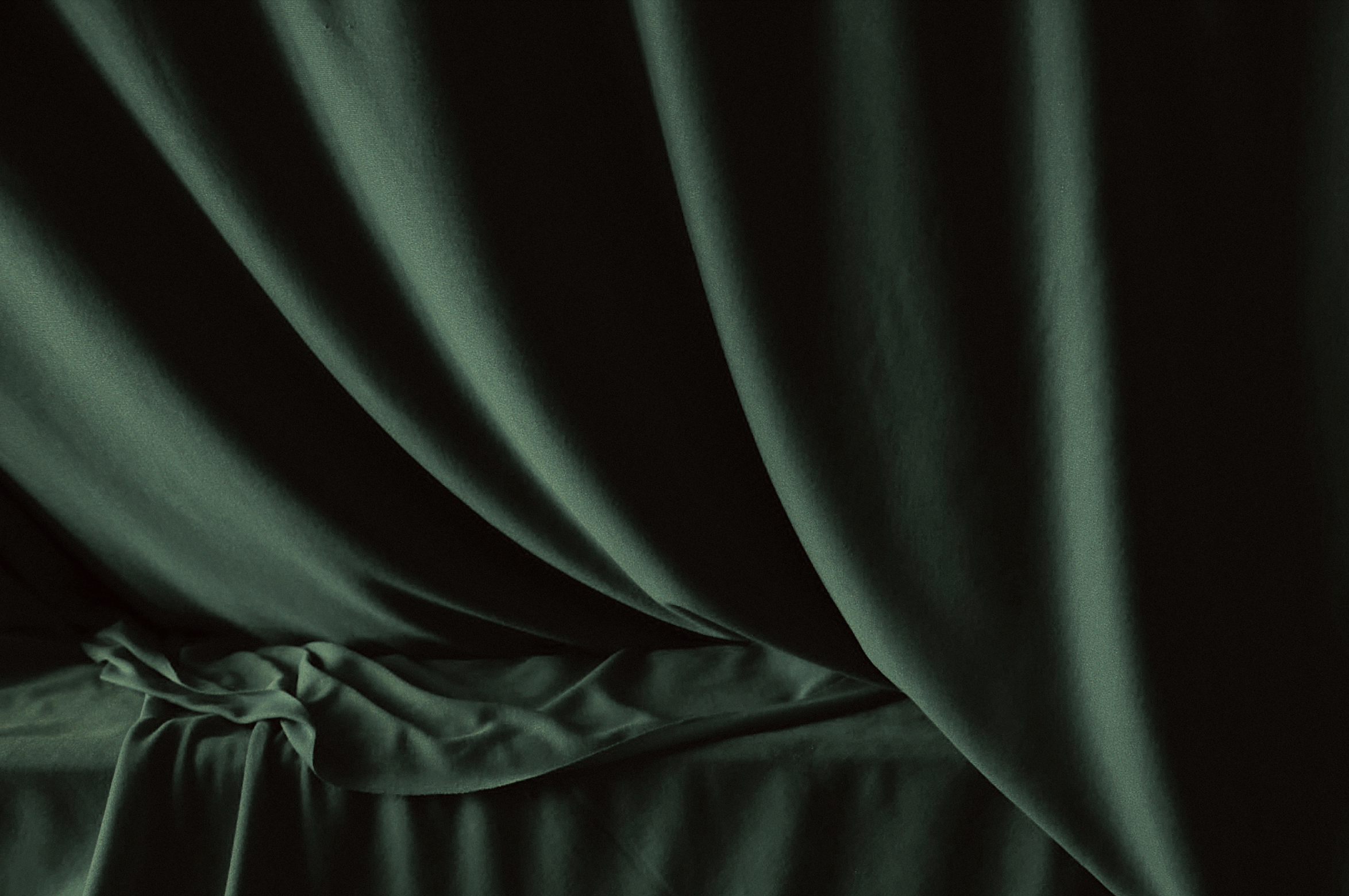 Dark green fabric with deep folds and soft shadows.
