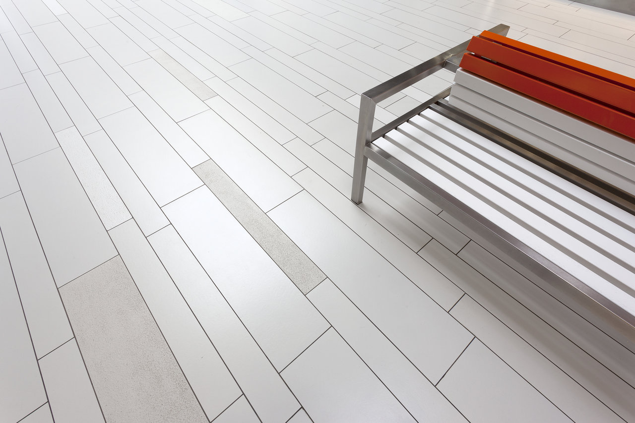 Light, elongated porcelain stoneware tiles, ideal for indoor and outdoor areas, with a bench.