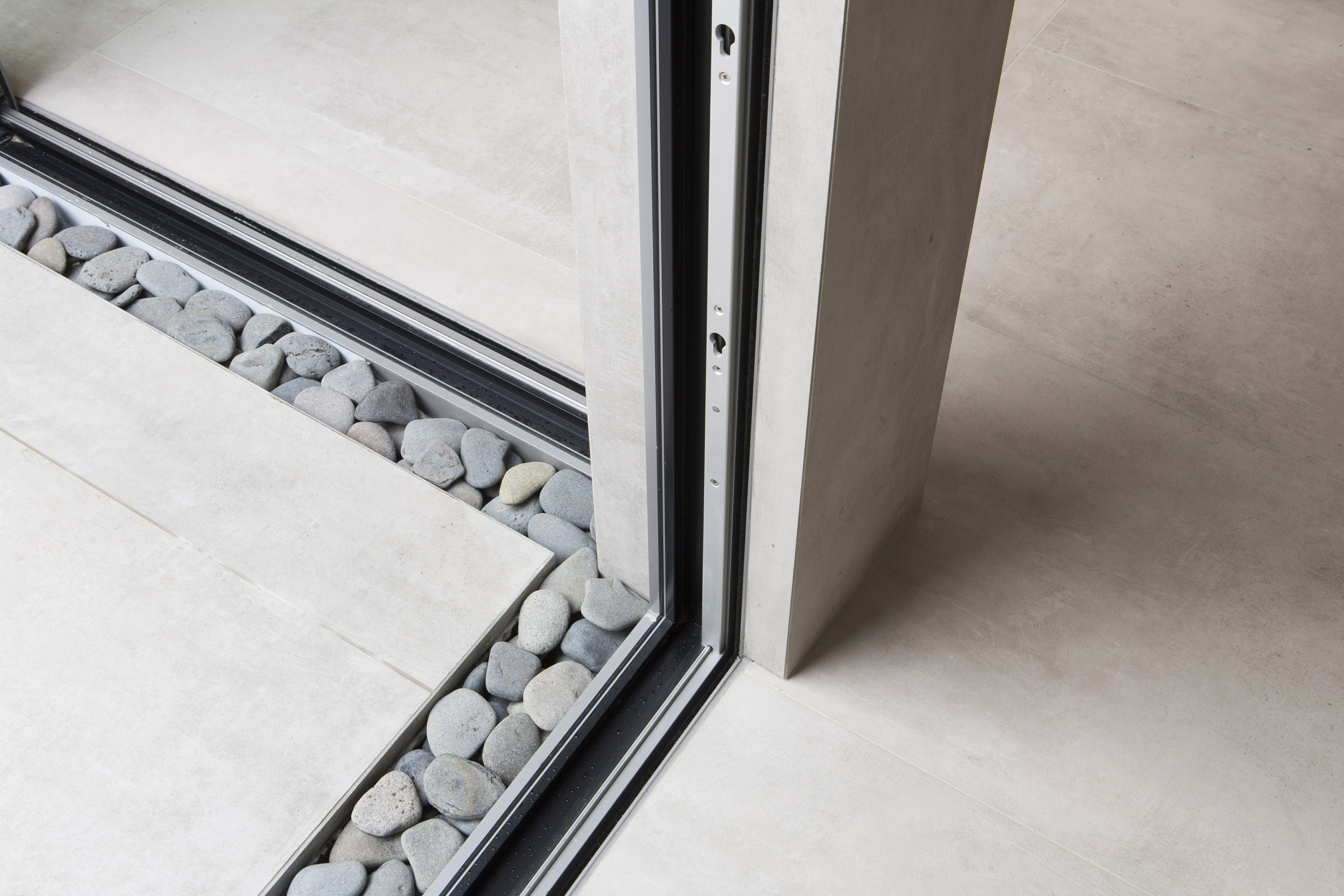 Light tiles with decorative gravel strip at indoor-outdoor transition.