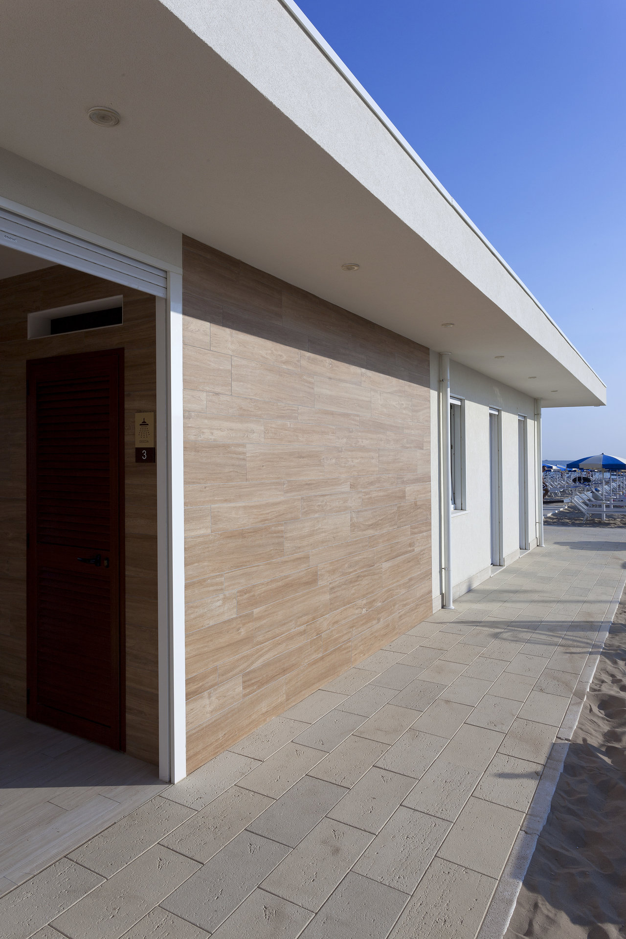 Facade with wood-look tiles and light outdoor flooring.