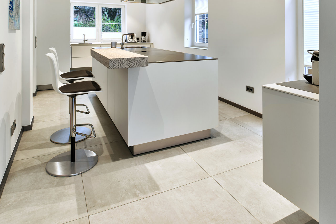 Light, large-format tiles in a modern kitchen with an island.