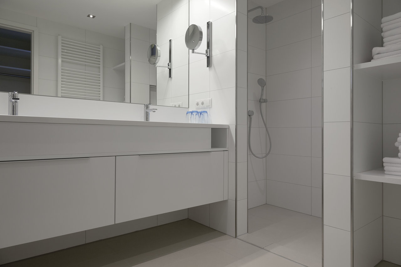 Modern bathroom with white wall and floor tiles by Porcelaingres.