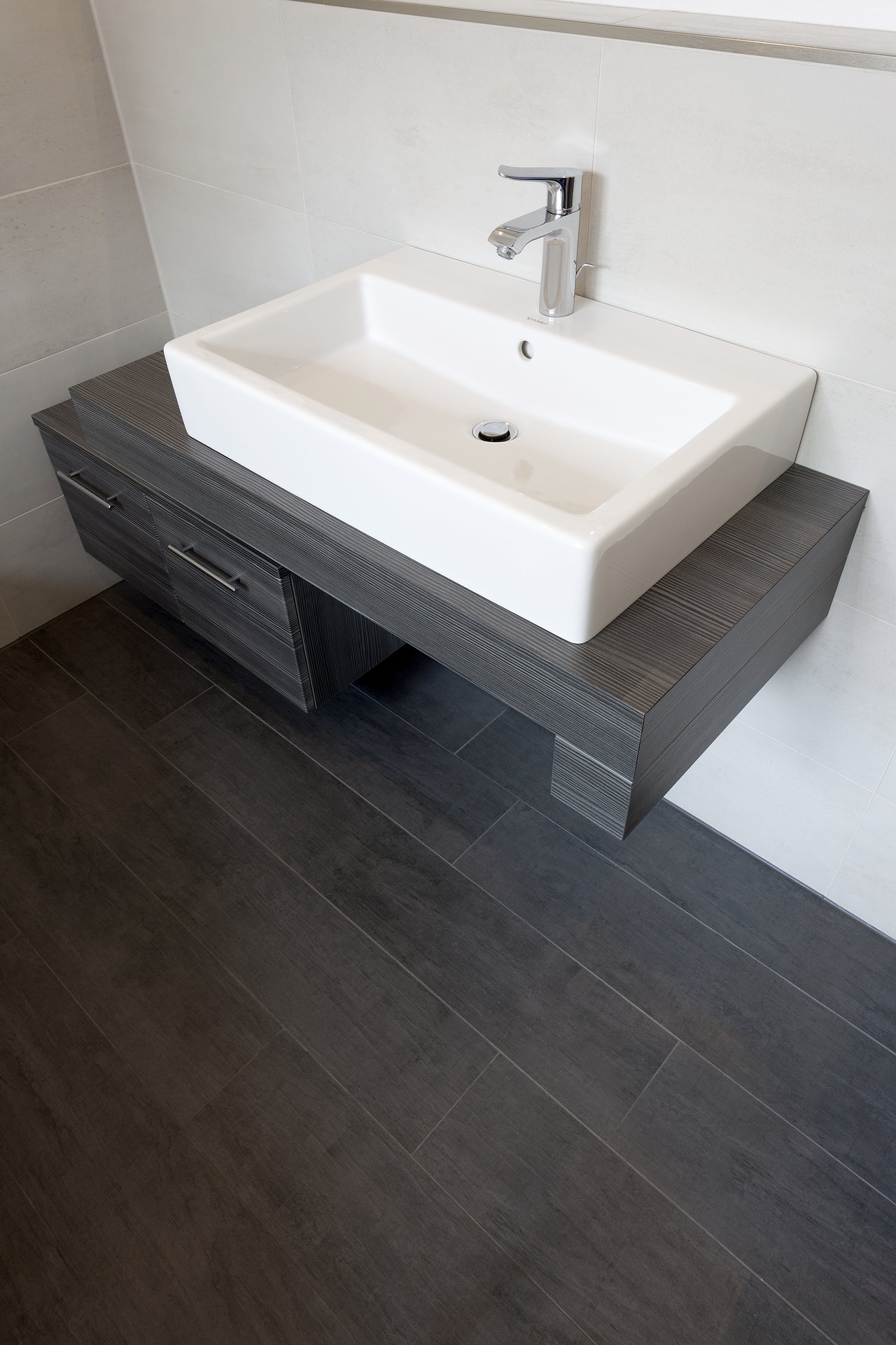 High-quality dark wood-effect floor tiles in bathroom with modern vanity.