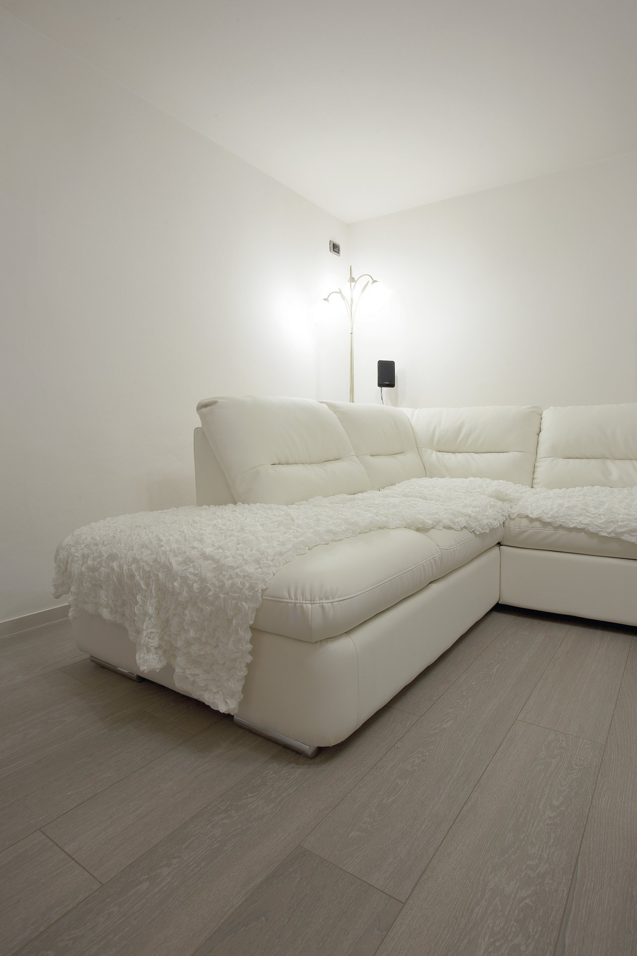 Bright living room with white sofa and grey wood-look tiles.